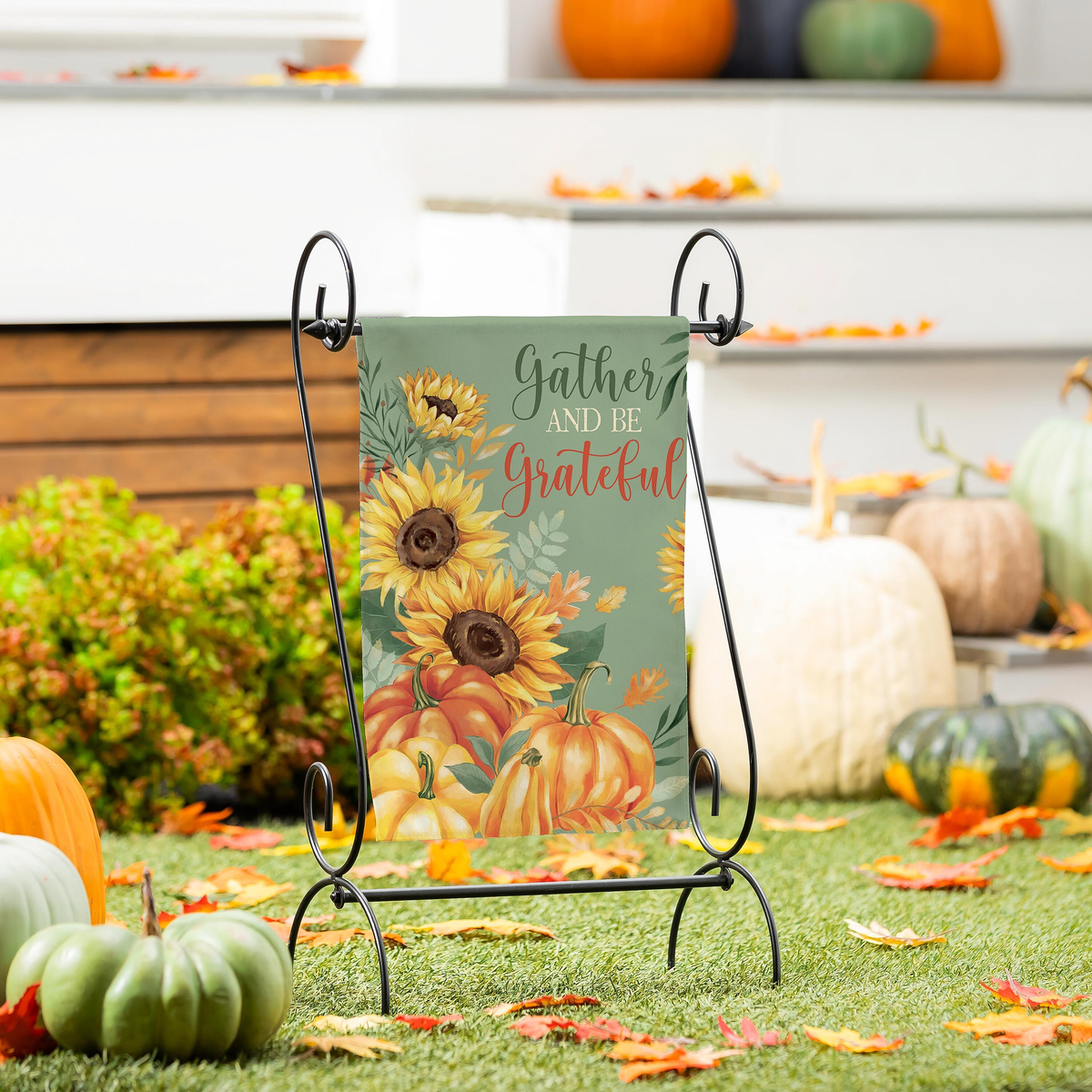 Evergreen Grateful Gatherings Suede Garden Flag -- displayed on a garden flag stand beside fall porch steps