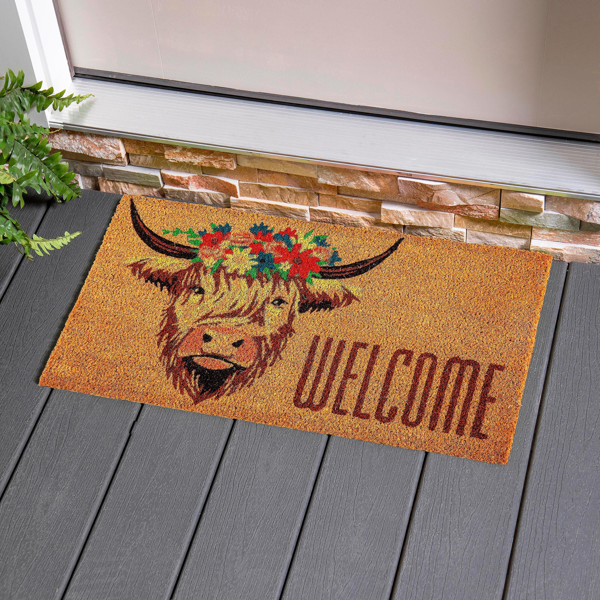 Evergreen Hillside Pasture Highland Cow Welcome Coir Mat -- at a front door on a grey deck