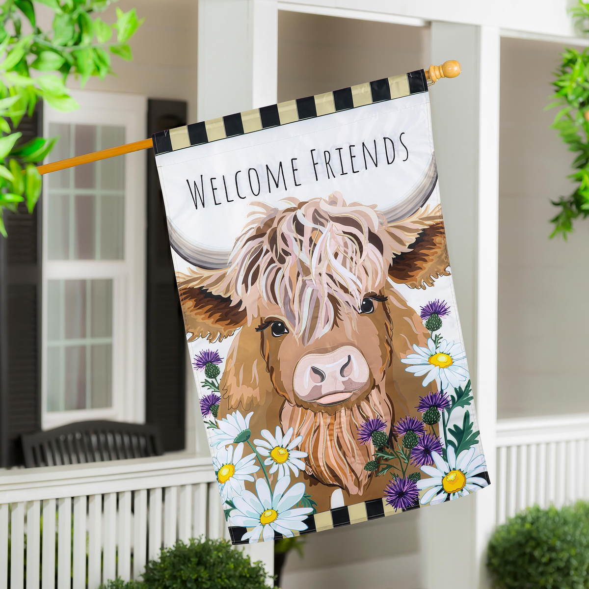 Evergreen Hillside Pasture Highland Cow Welcome Friends Applique House Flag -- hanging from a porch pole