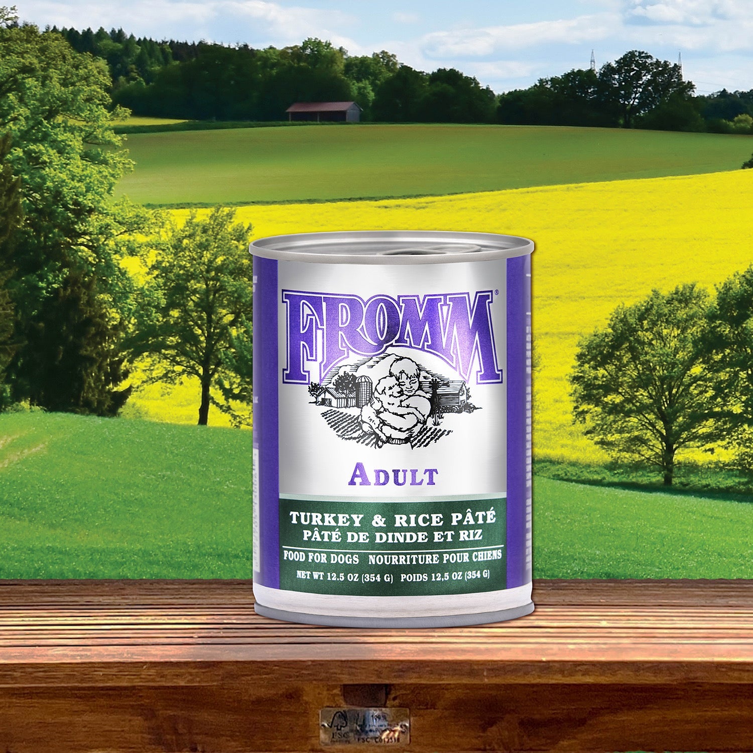 A can of Fromm Classic Adult Turkey & Rice Pâté on a wooden rail with rolling farm fields behind