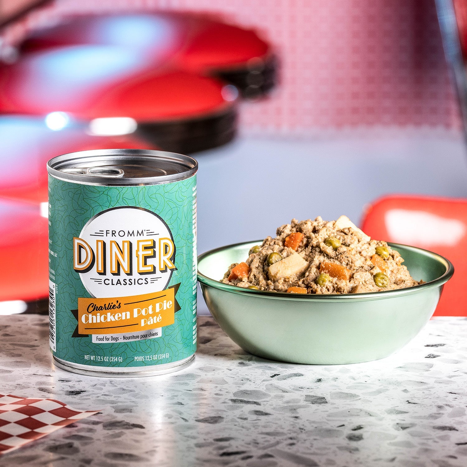 A can of Fromm Diner Classics Charlie's Chicken Pot Pie Pâté beside a bowl of the food on a retro diner counter