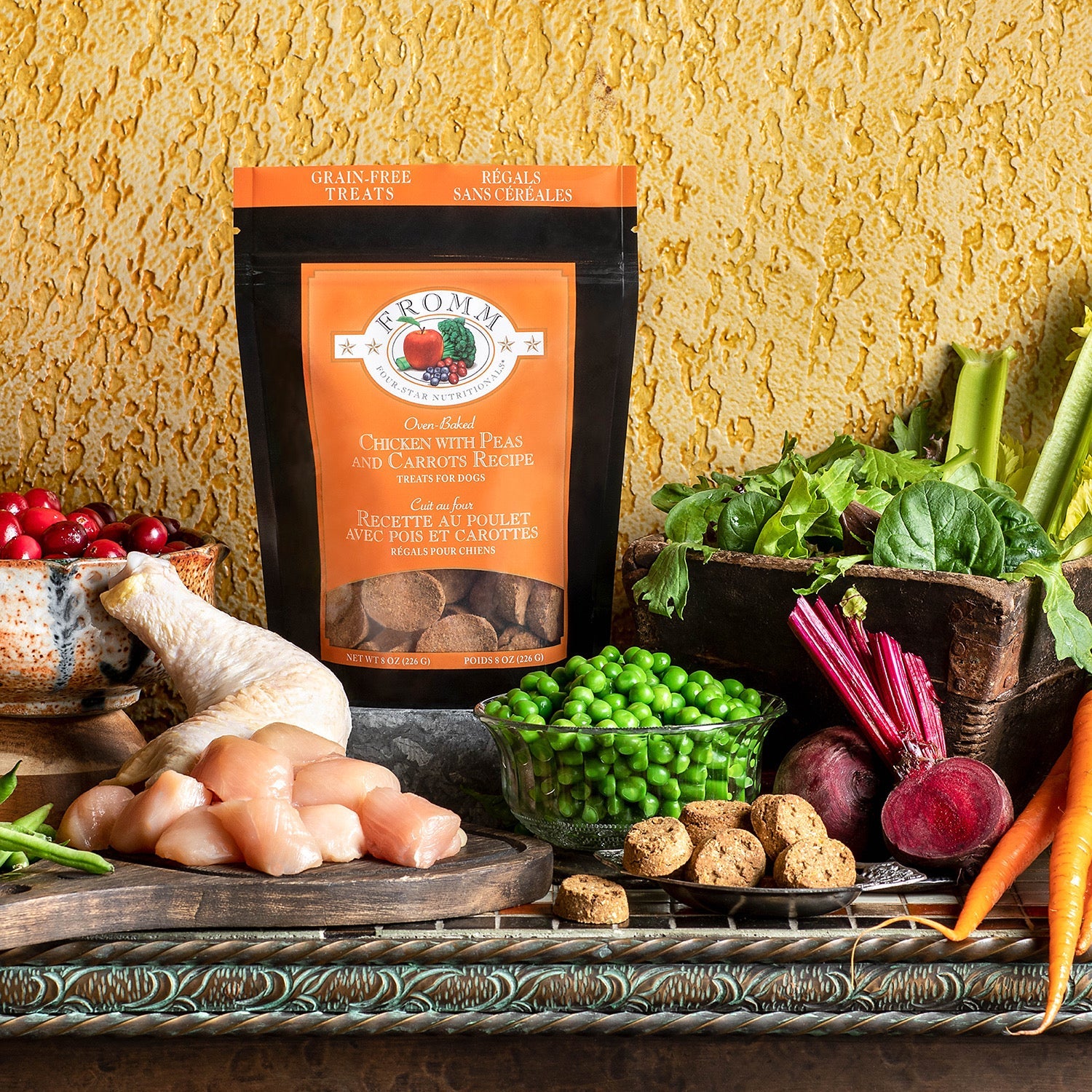 Bag of Fromm Four-Star Chicken with Peas and Carrots treats styled with raw chicken, green peas, carrots, beets, and cranberries