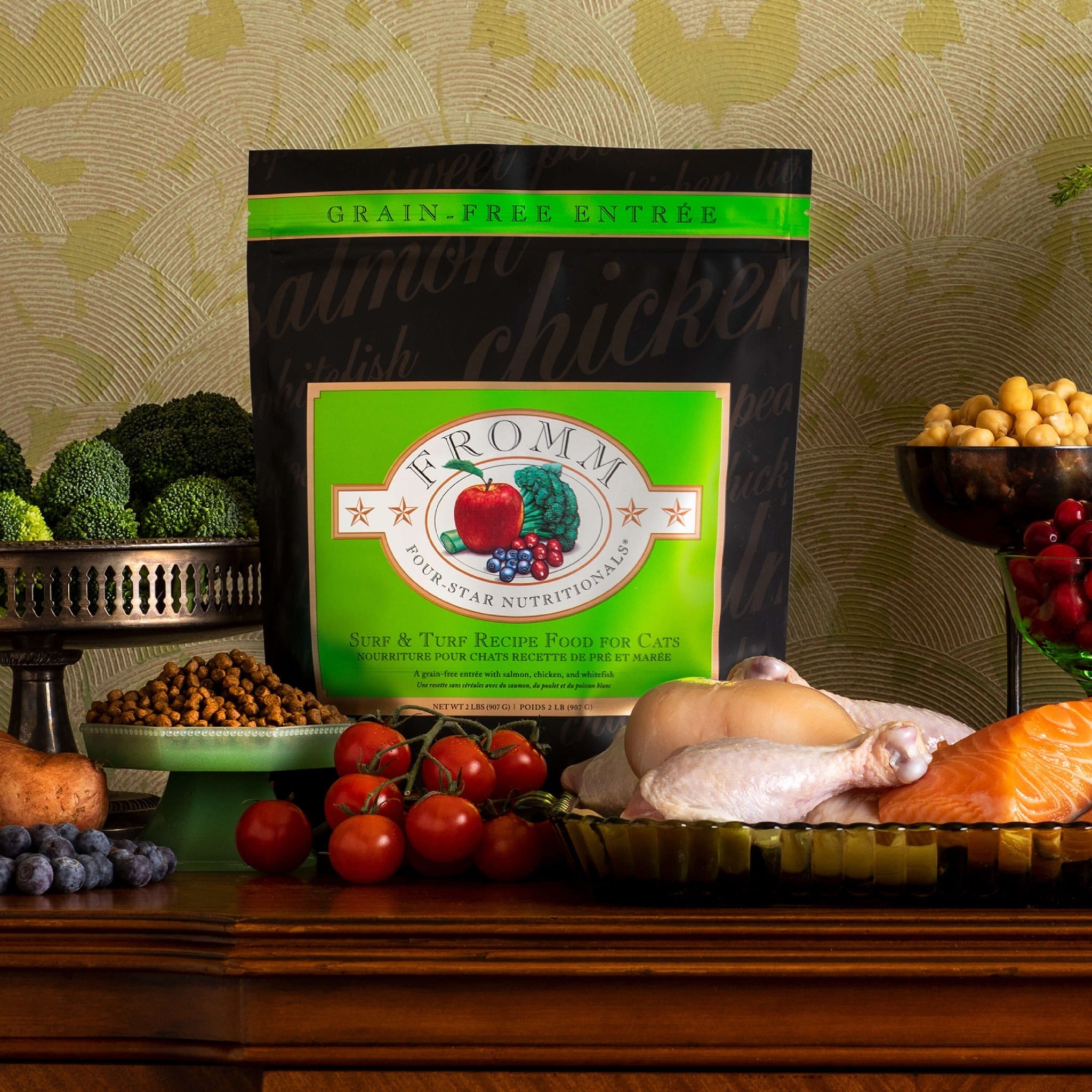 Fromm Four-Star Surf & Turf Recipe bag on a table with fresh salmon, chicken, and vegetables