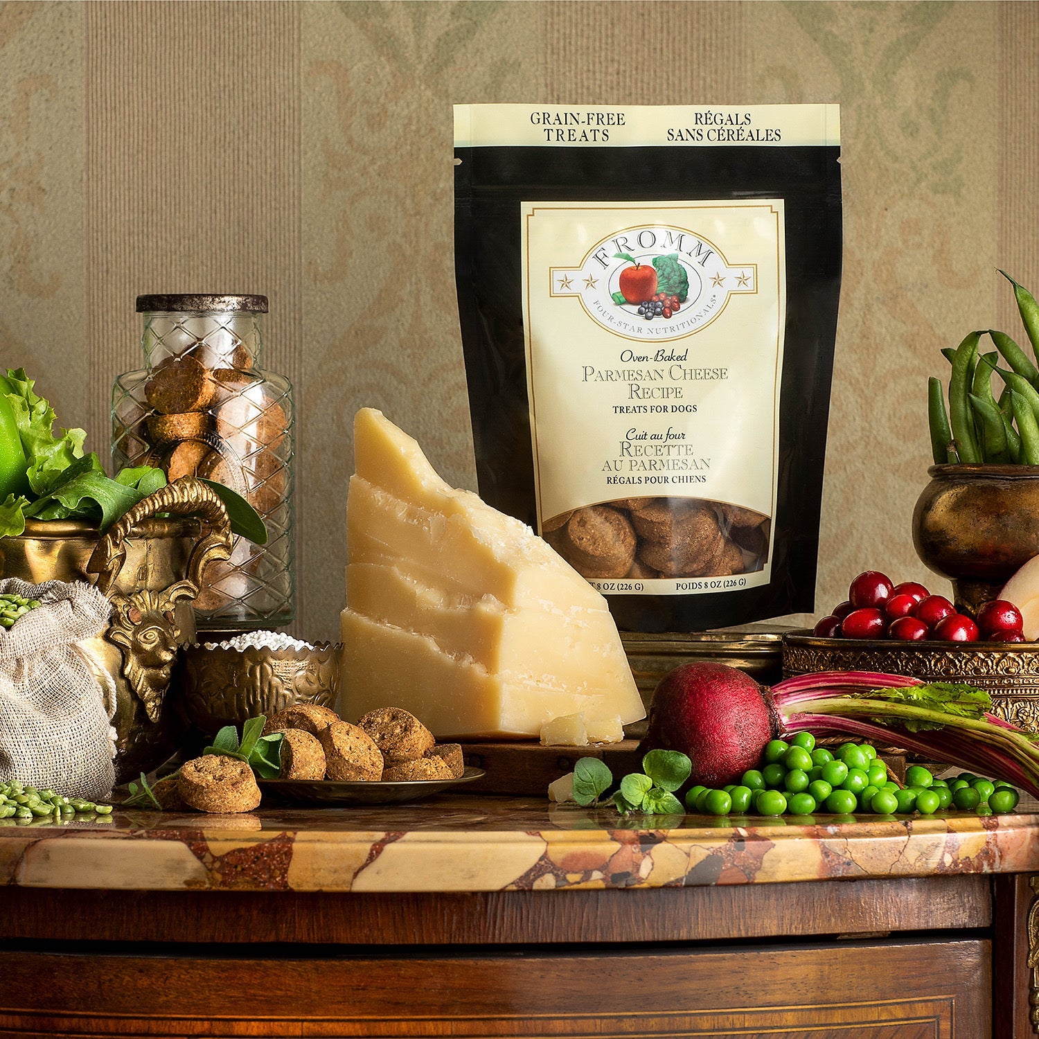 Bag of Fromm Four-Star Parmesan Cheese Recipe treats styled with a parmesan wedge, peas, cranberries, beets, and fresh greens