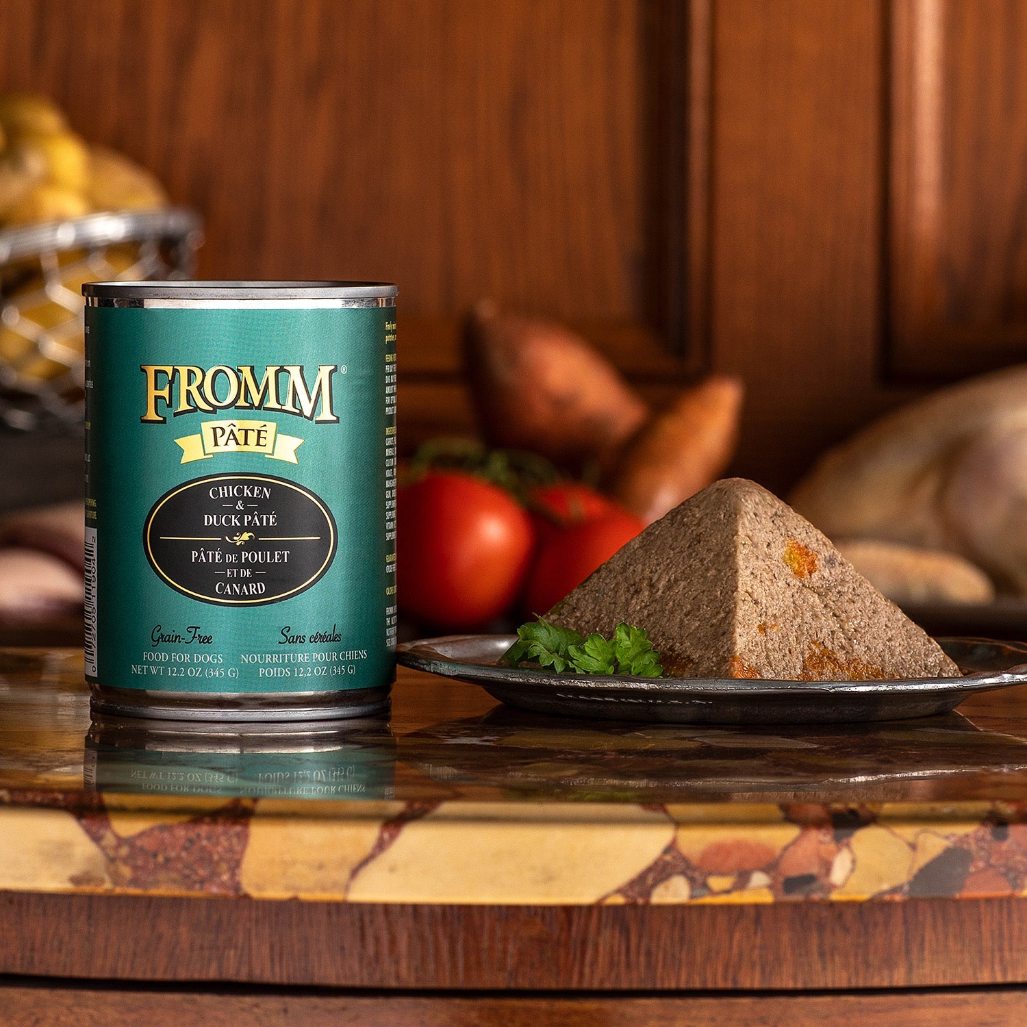 A can of Fromm Pâté Chicken & Duck beside a plated pâté wedge with tomatoes and parsley
