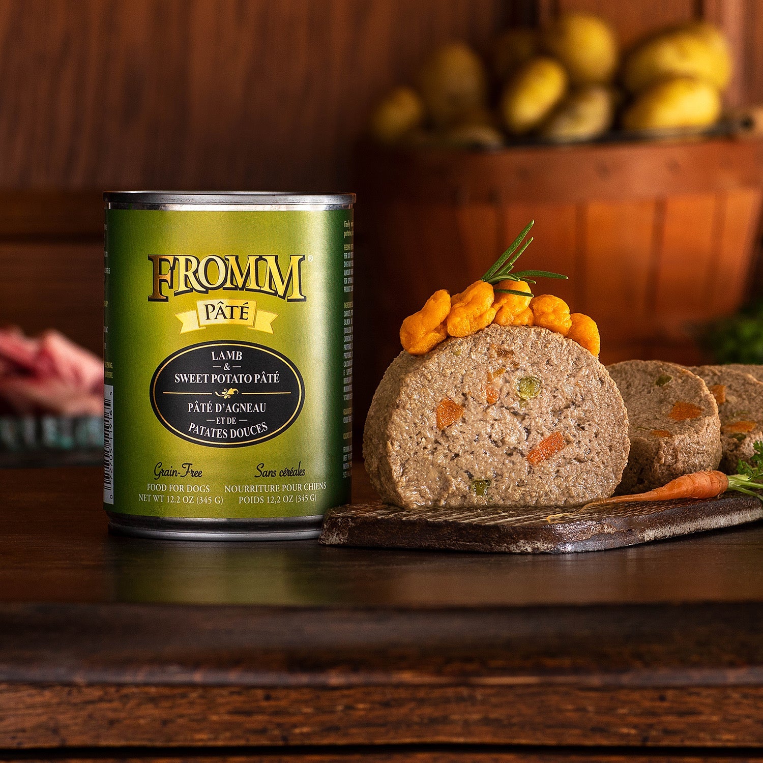 A can of Fromm Pâté Lamb & Sweet Potato beside a sliced pâté portion garnished with sweet potato on a wooden board