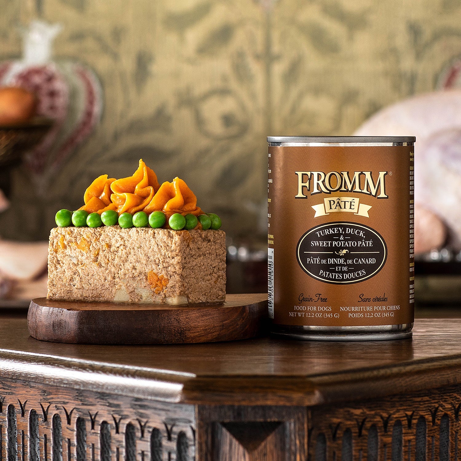 A can of Fromm Pâté Turkey, Duck, & Sweet Potato beside sliced pâté topped with sweet potato purée and green peas