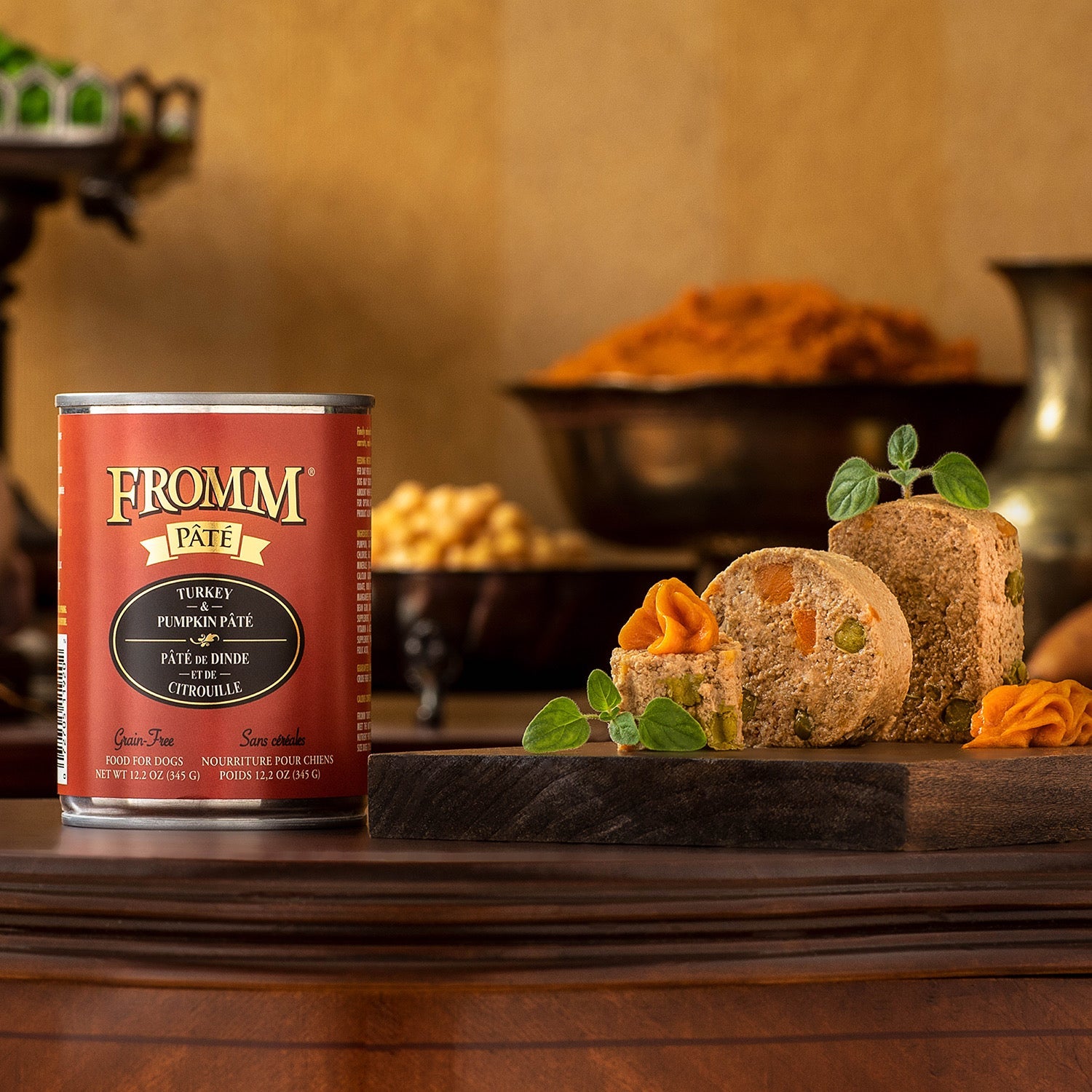 A can of Fromm Pâté Turkey & Pumpkin beside sliced pâté garnished with pumpkin purée on a wooden board