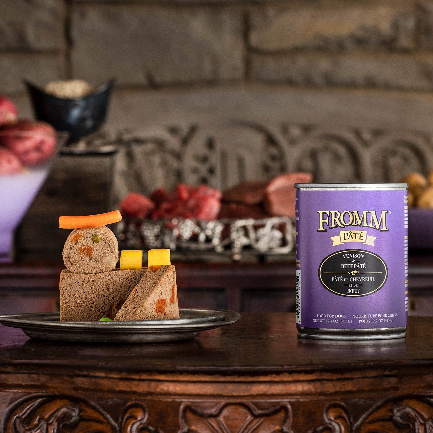 A can of Fromm Pâté Venison & Beef beside a plated pâté round and slices garnished with carrot and squash
