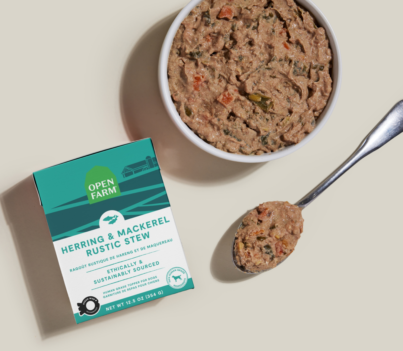 Open Farm Herring & Mackerel Rustic Stew Topper for Dogs 12.5 oz carton beside a bowl of food