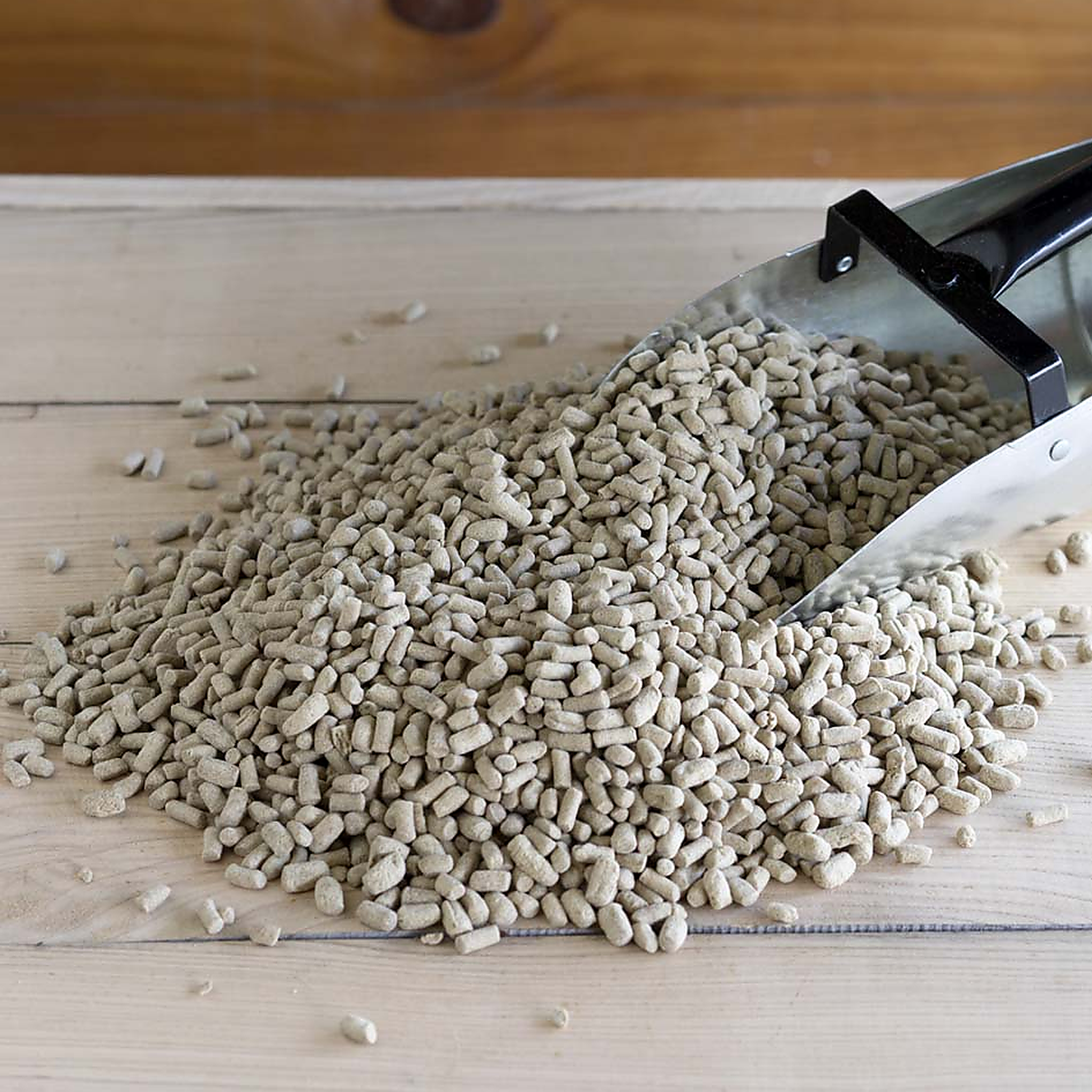 Close-up of extruded stabilized rice bran pellets poured from a feed scoop