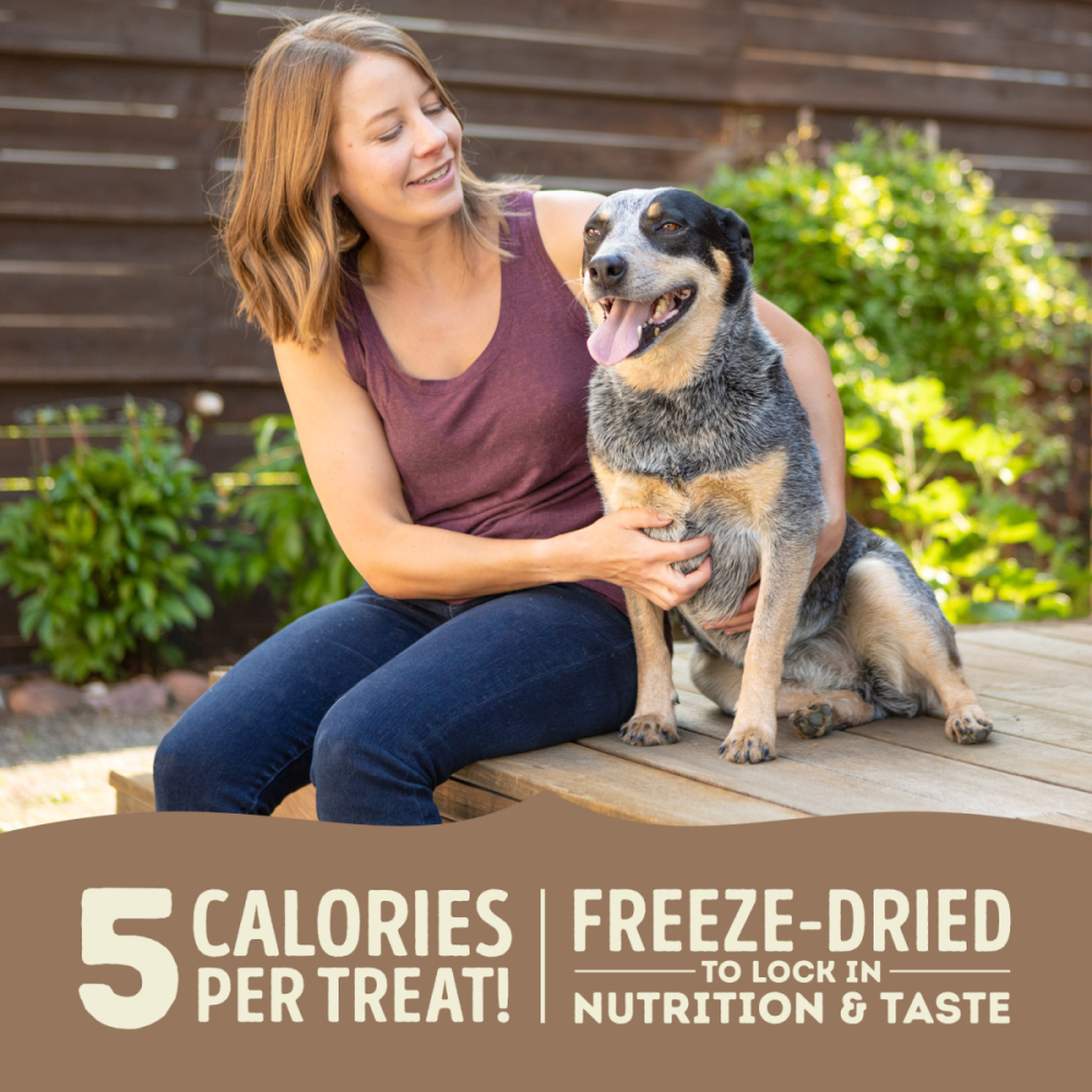 Woman sitting outdoors with an Australian Cattle Dog, ACANA Free-Run Duck treats have 5 calories per treat and are freeze-dried to lock in nutrition and taste