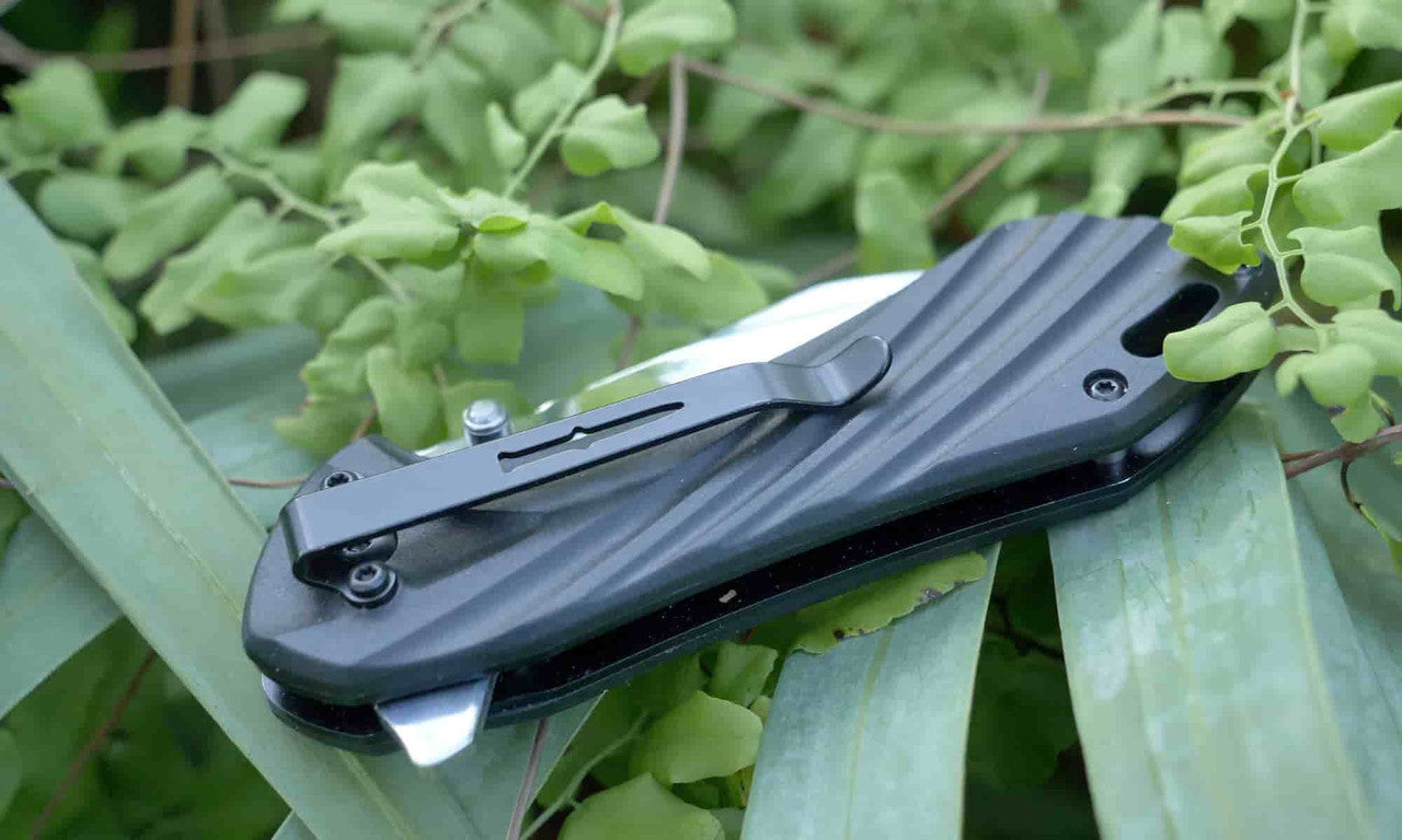 Camillus Chunk folding knife closed showing stainless pocket clip and sculpted black glass-filled nylon handle resting on green foliage