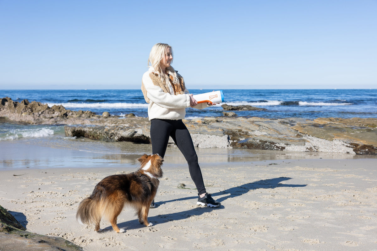Woman at the beach launching a ball for her dog with the Chuckit! Cannon 16M