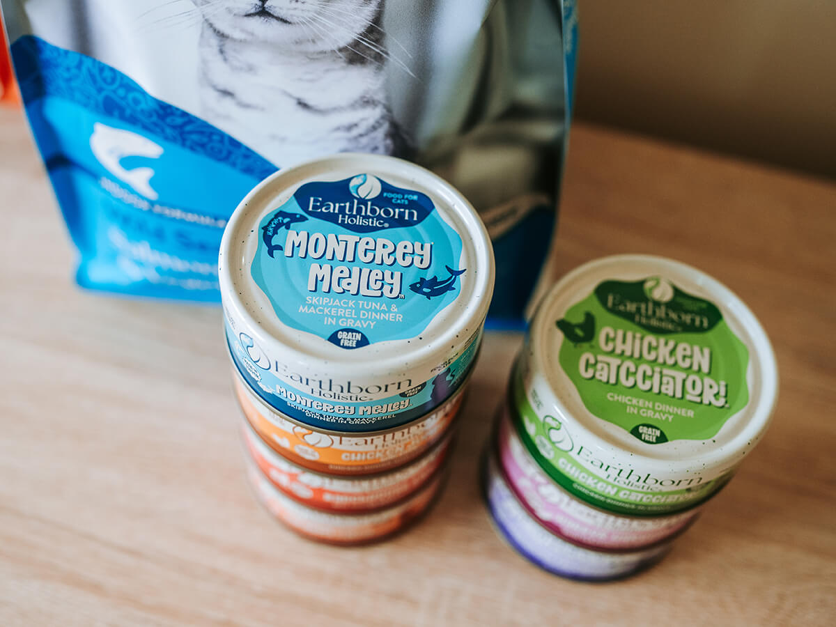 Earthborn Holistic Monterey Medley wet cat food can in front of Wild Sea Catch dry food and other Earthborn products