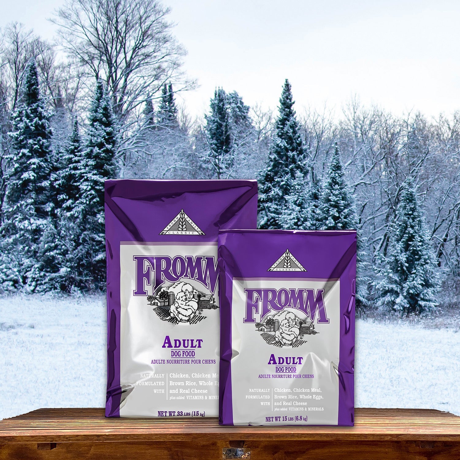 Two sizes of Fromm Classic Adult bags on a bench before a snowy evergreen forest