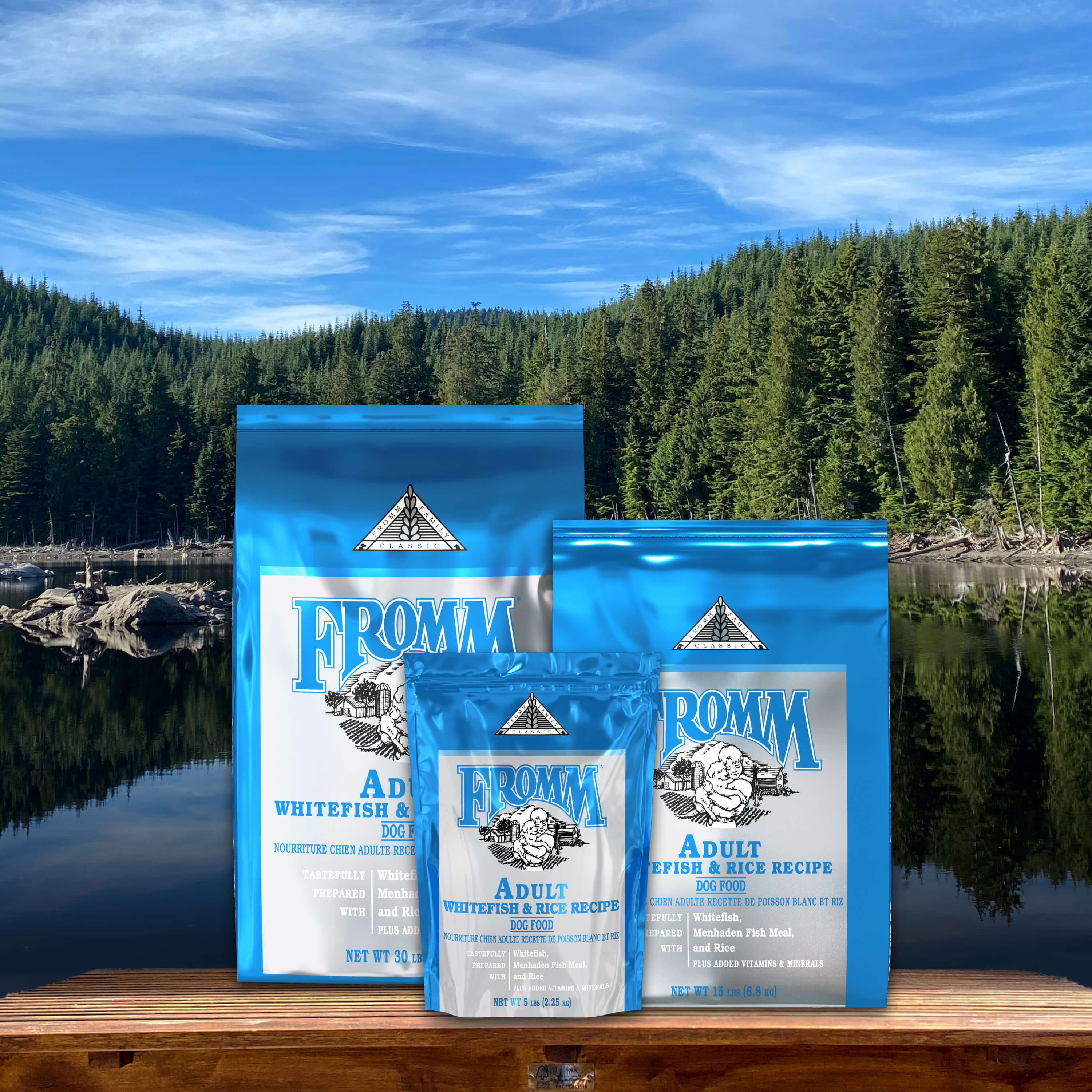 Three sizes of Fromm Classic Whitefish and Rice bags on a dock at a forest lake