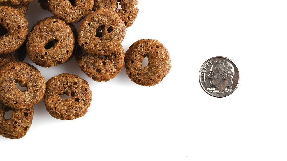 A pile of Fromm Crunchy O's ring treats next to a dime for scale