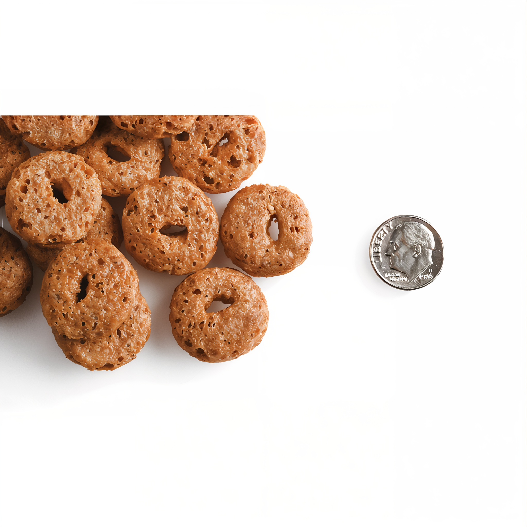 A pile of O-shaped Fromm Crunchy O's Peanut Butter Jammers treats next to a dime for scale