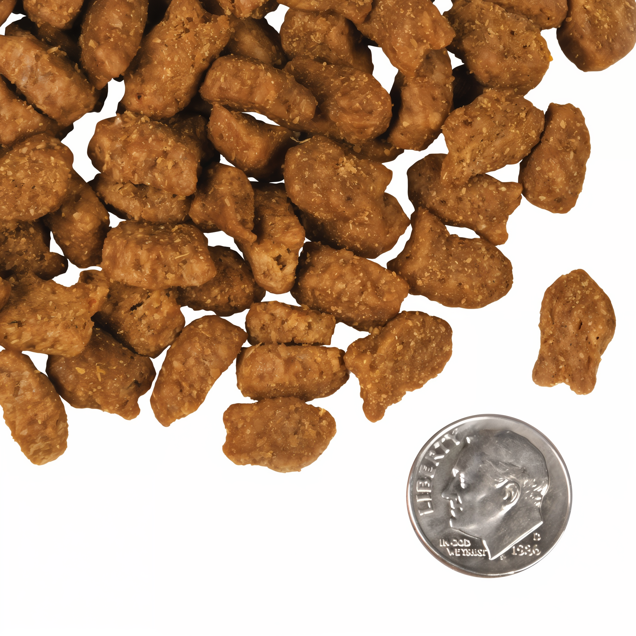 A small pile of Fromm Four-Star Trout & Whitefish fish-shaped kibble next to a dime for scale