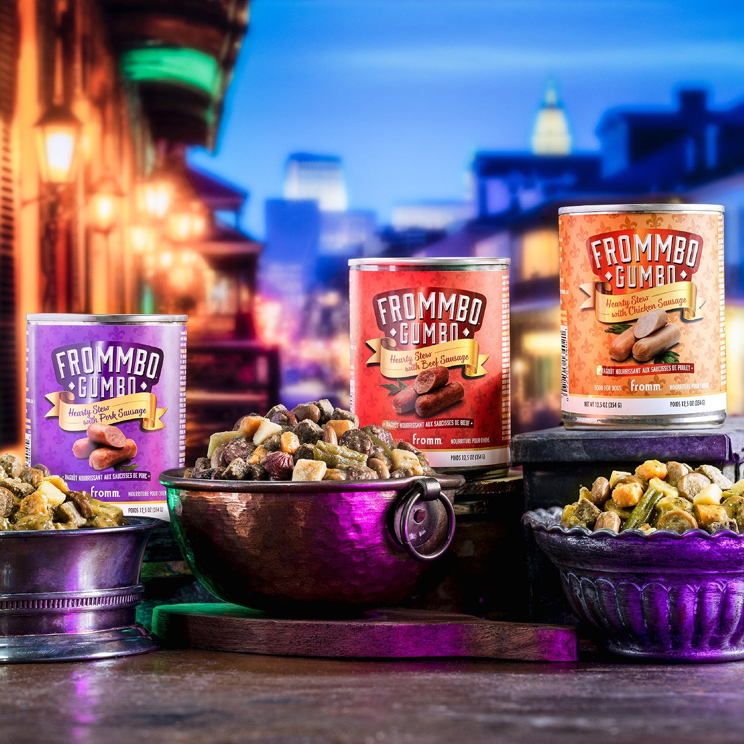 Three Frommbo Gumbo hearty stew cans with filled bowls in a neon-lit night street scene