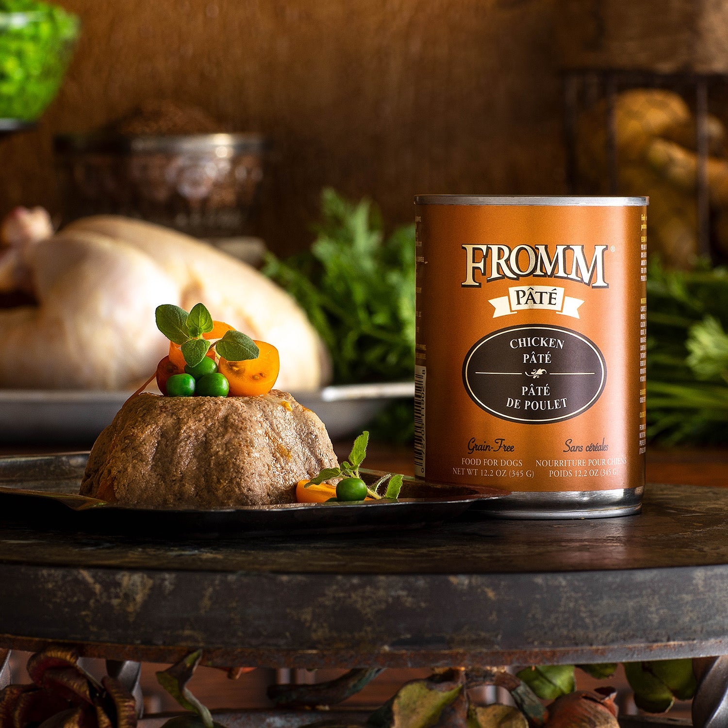 A can of Fromm Pâté Chicken beside molded pâté garnished with peas, tomatoes, and fresh oregano