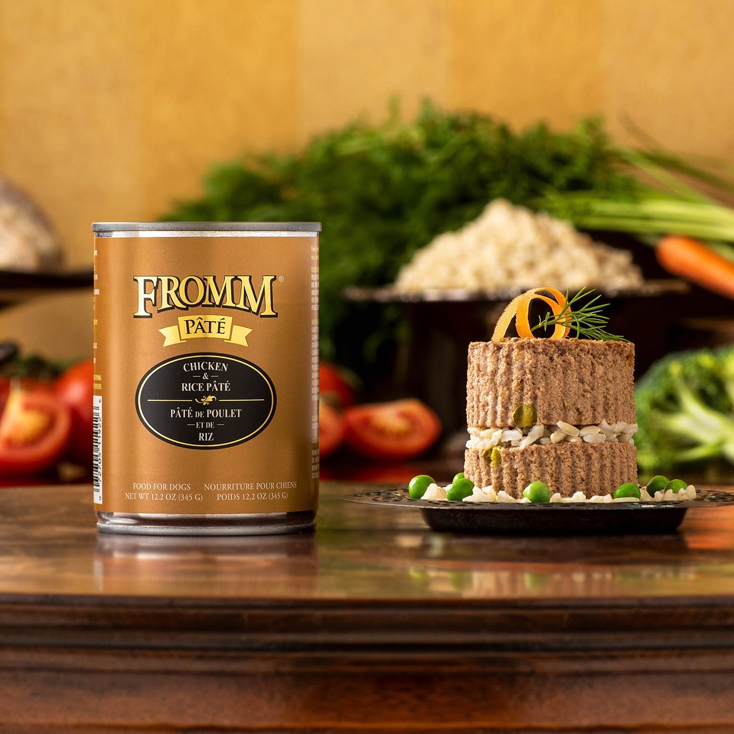 A can of Fromm Pâté Chicken & Rice beside a layered pâté plated with brown rice, peas, and a carrot curl