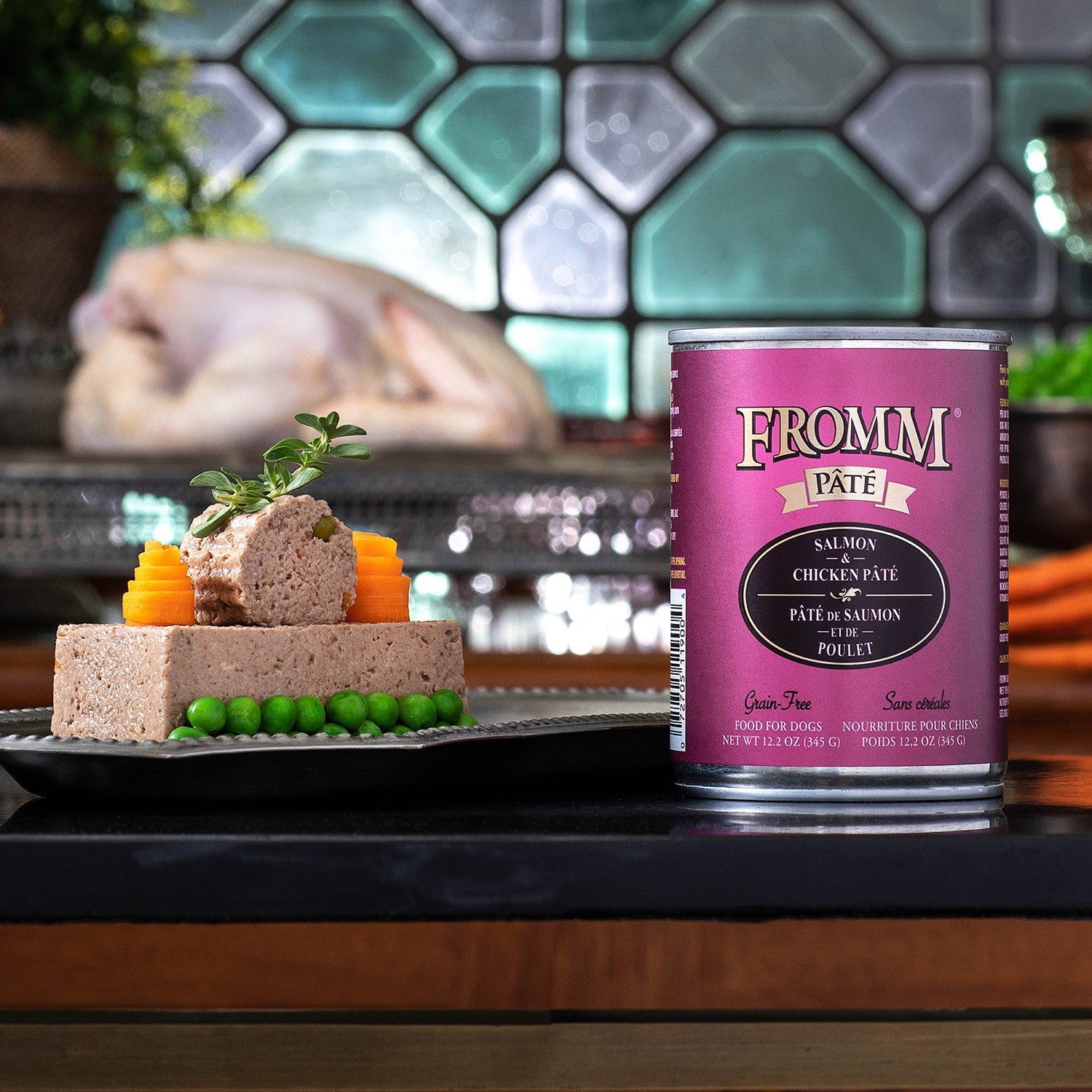A can of Fromm Pâté Salmon & Chicken beside an elegantly plated pâté with carved carrots and peas