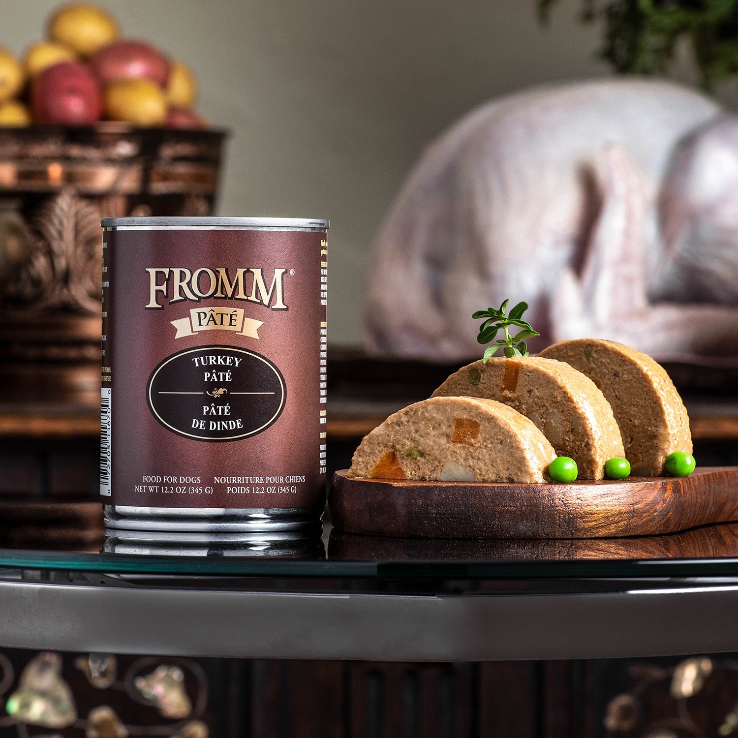 A can of Fromm Pâté Turkey beside sliced pâté with visible carrots and peas on a wooden board