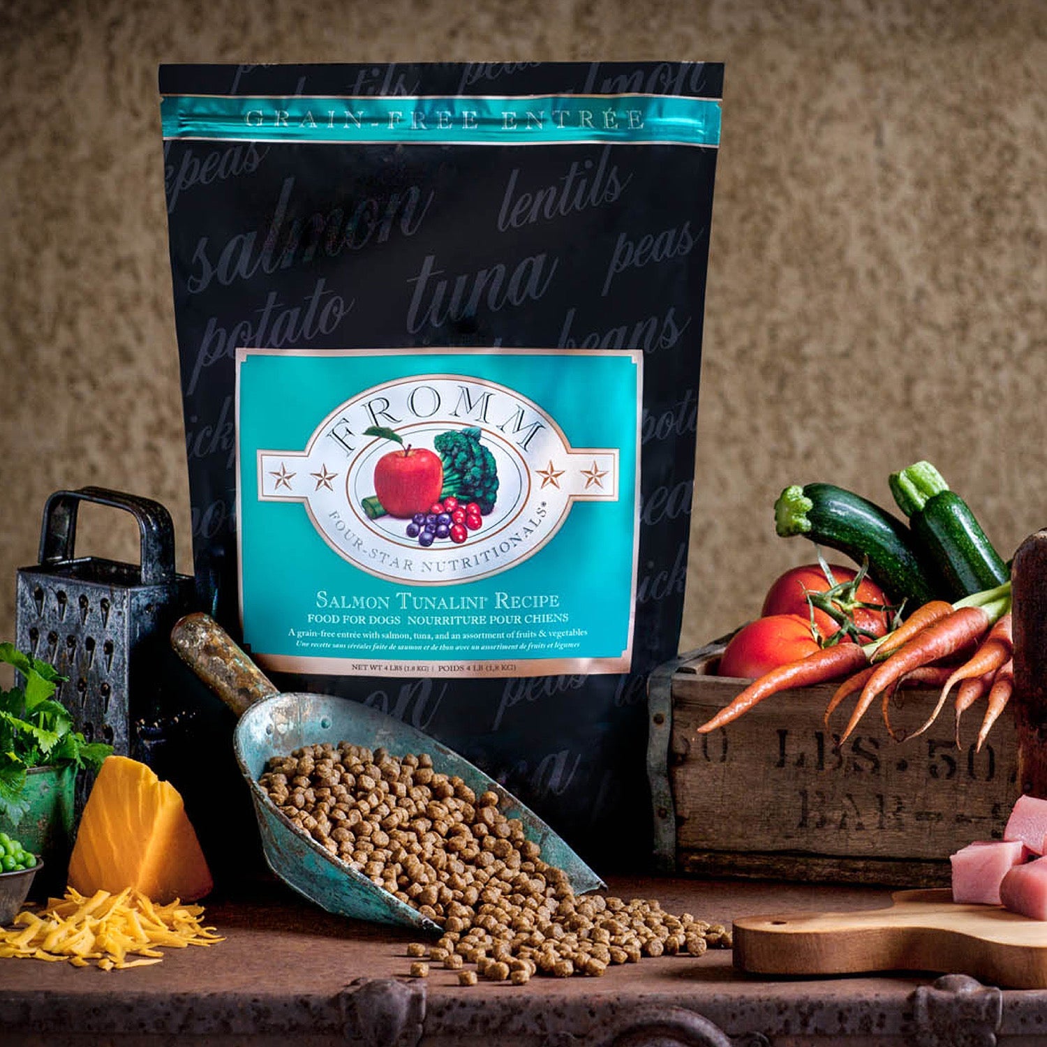 Grain-free Salmon Tunalini bag with a scoop of kibble, zucchini, carrots, tomatoes, and cheese