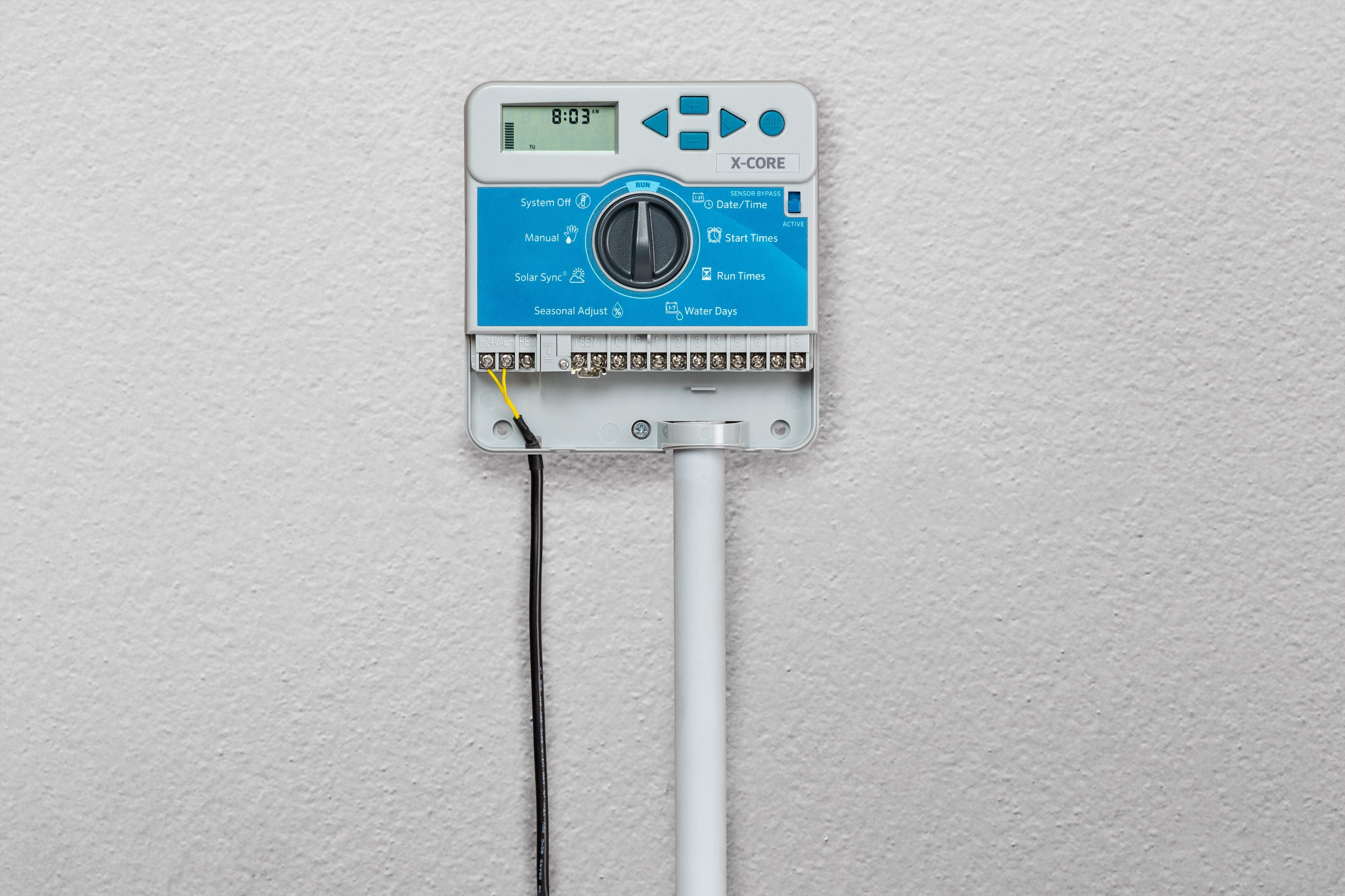 Hunter XC-600i X-Core indoor controller installed on an interior garage wall with conduit dropping to the valve box