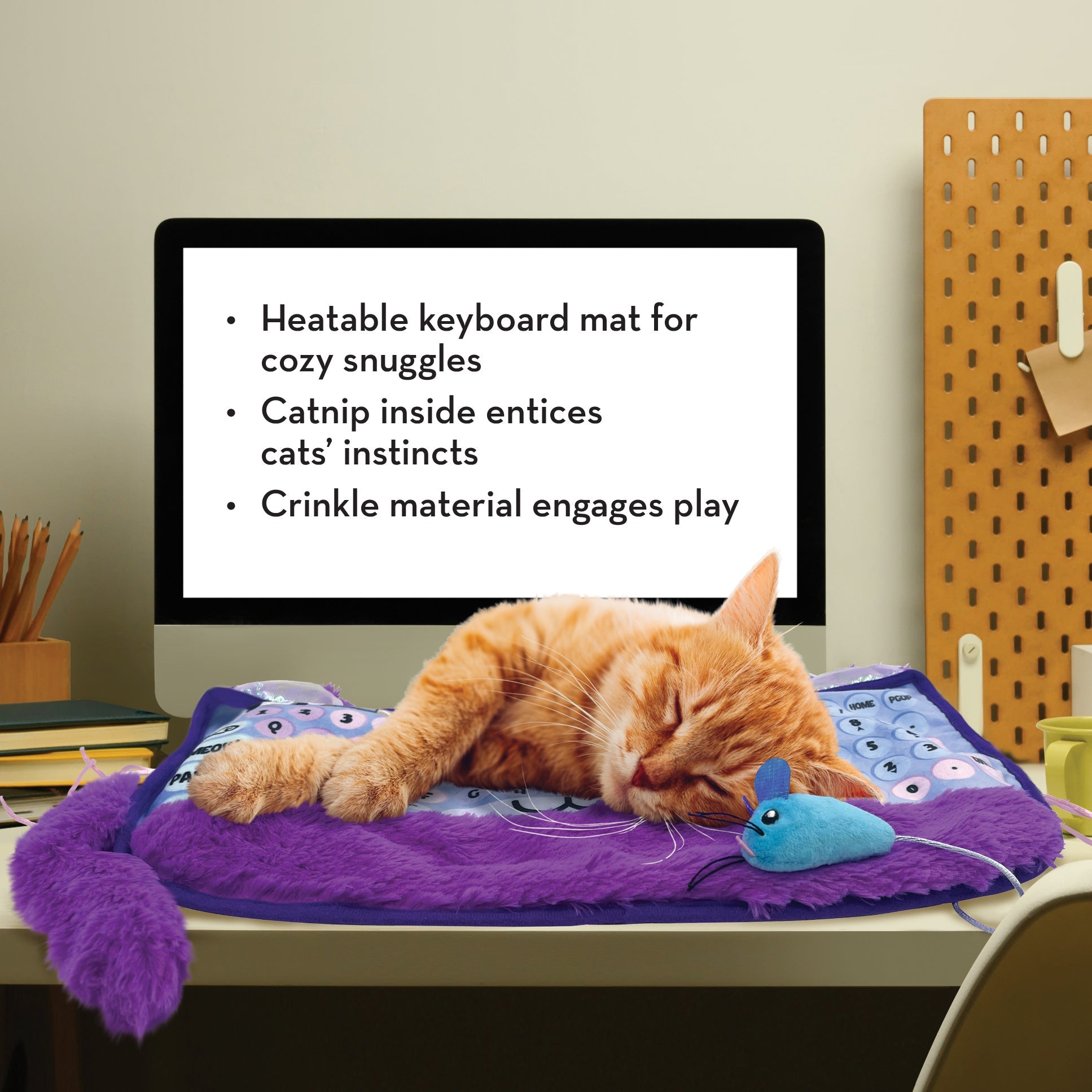Orange cat napping on the KONG Comfort Key Play Mat at a desk