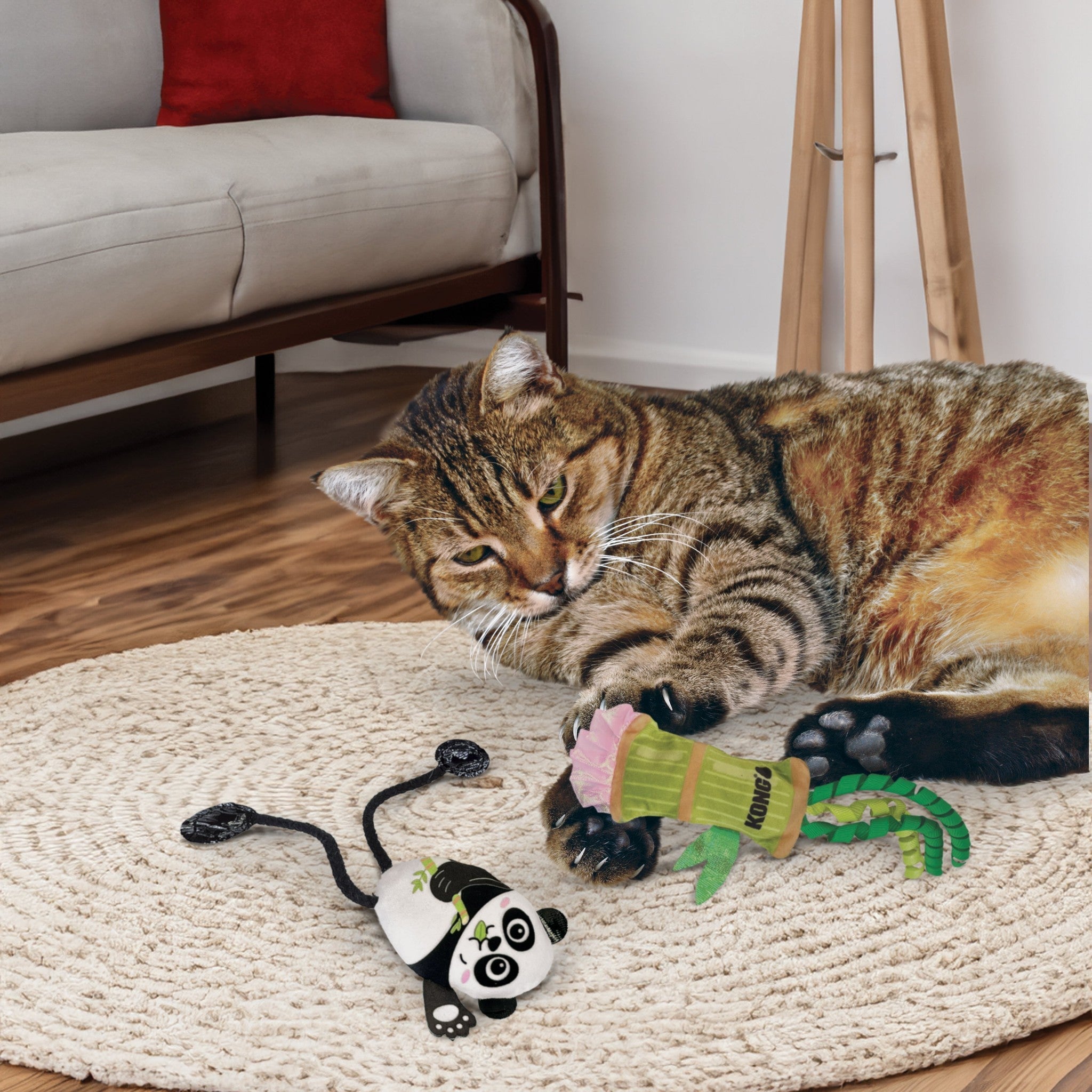 Tabby cat batting the KONG Scrattles Panda and bamboo-shoot toys