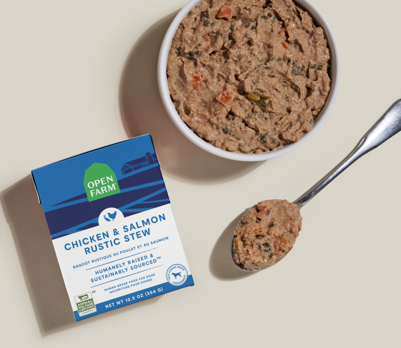 Open Farm Chicken & Salmon Rustic Stew Wet Dog Food 12.5 oz carton beside a bowl of food