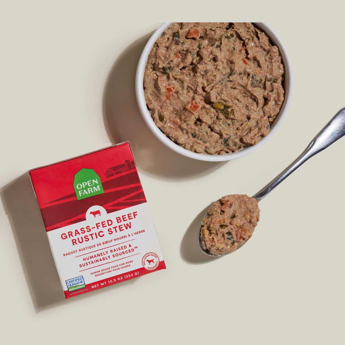 Open Farm Grass-Fed Beef Rustic Stew Wet Dog Food -- 12.5 oz carton beside a bowl of food