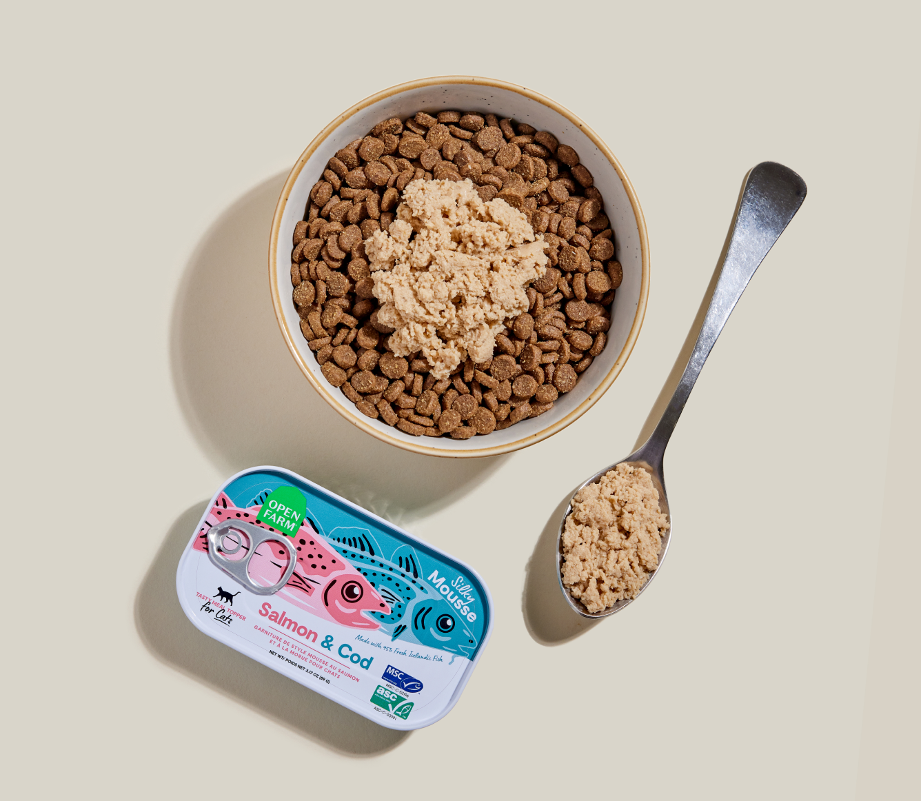 Open Farm Salmon & Cod Topper served over kibble in a bowl with a spoon
