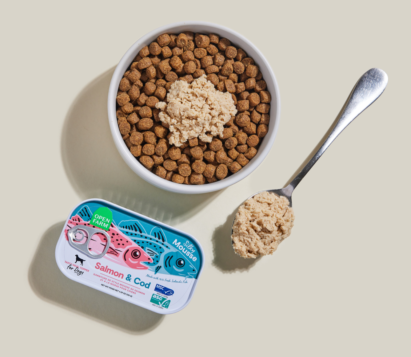 Open Farm Salmon & Cod Topper served over kibble in a bowl with a spoon