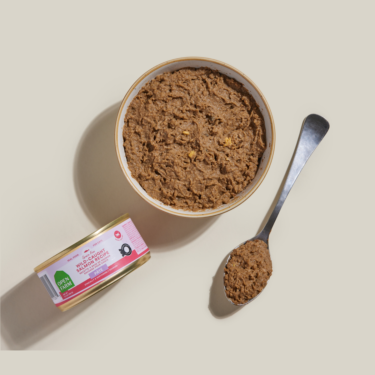 Open Farm Wild-Caught Salmon Pâté for Cats -- open farm salmon pâté served in a bowl beside the 5.3 oz can and a spoon