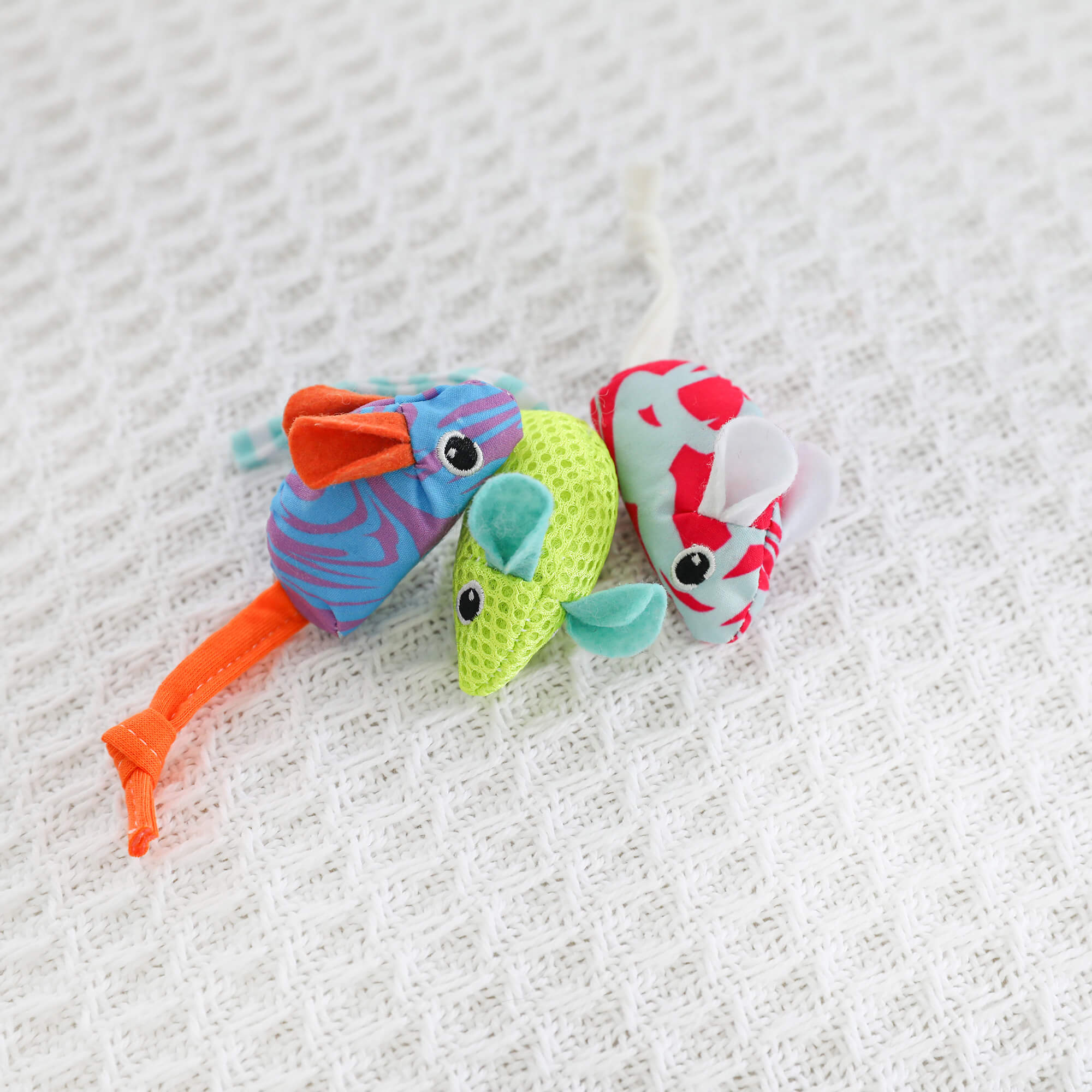 Three Quirky Kitty Cool Mice toys grouped together on a white waffle blanket