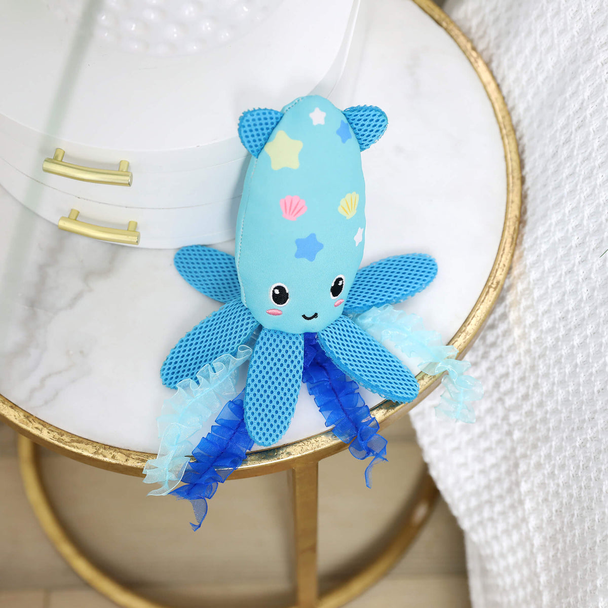 Octopurr Kicker octopus toy resting on a round marble side table with gold rim