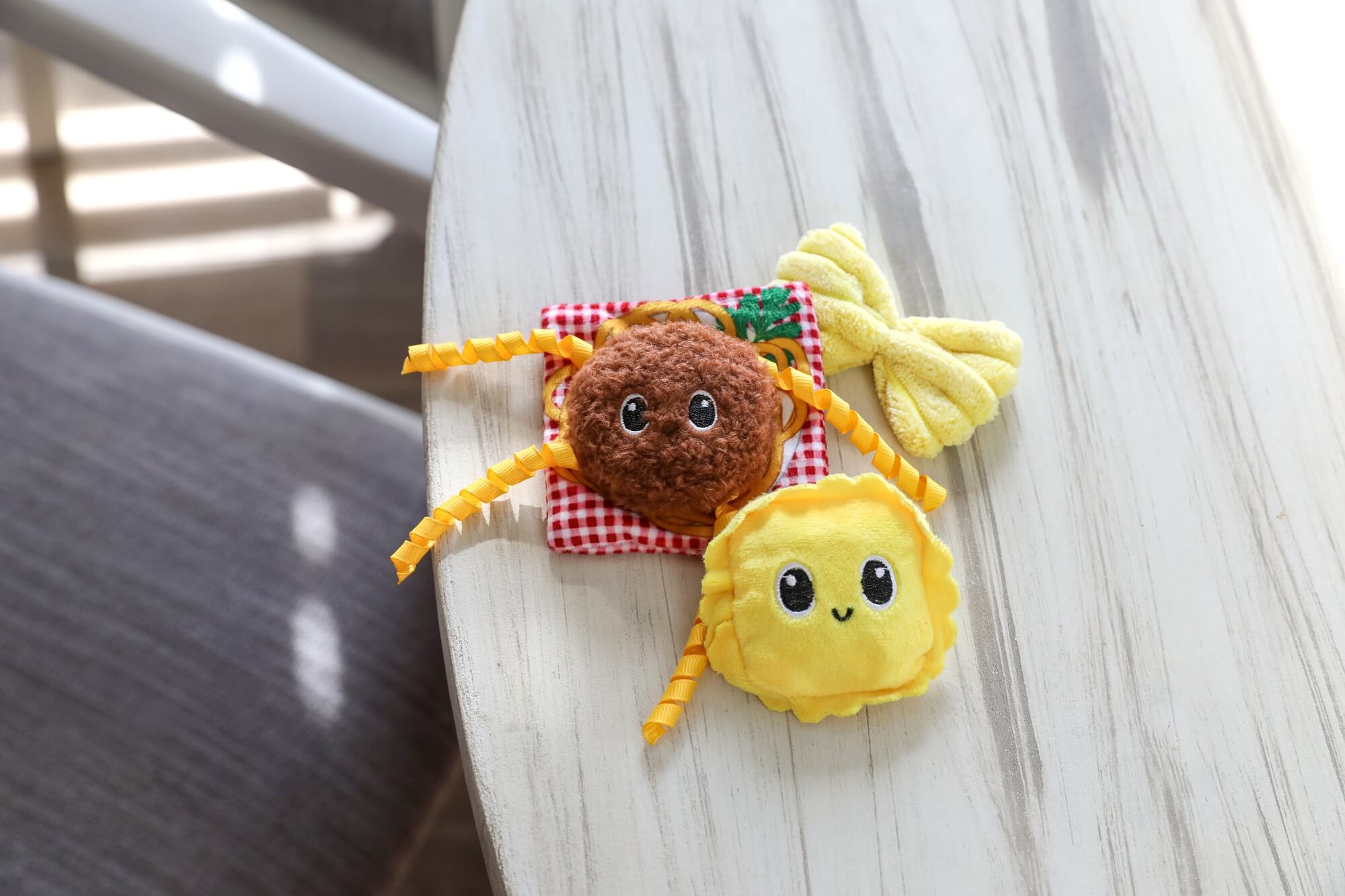Quirky Kitty Pasta Pals meatball, ravioli, and bowtie toys on a white wood table
