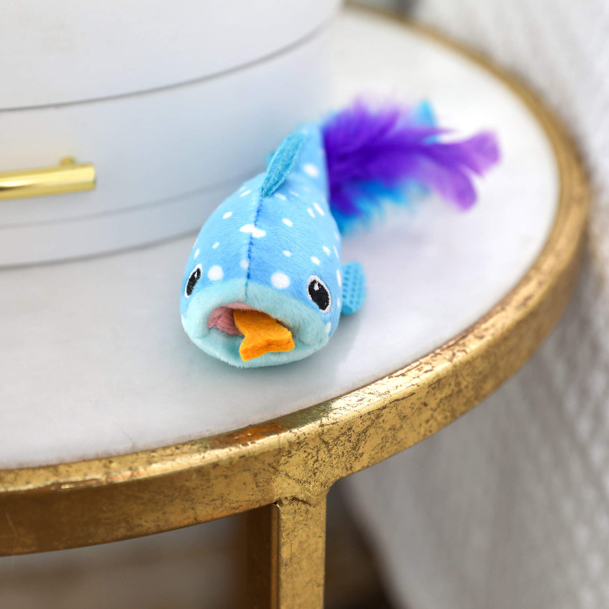 Quirky Kitty Whale Shark Chomper on a marble side table with felt fish in its mouth