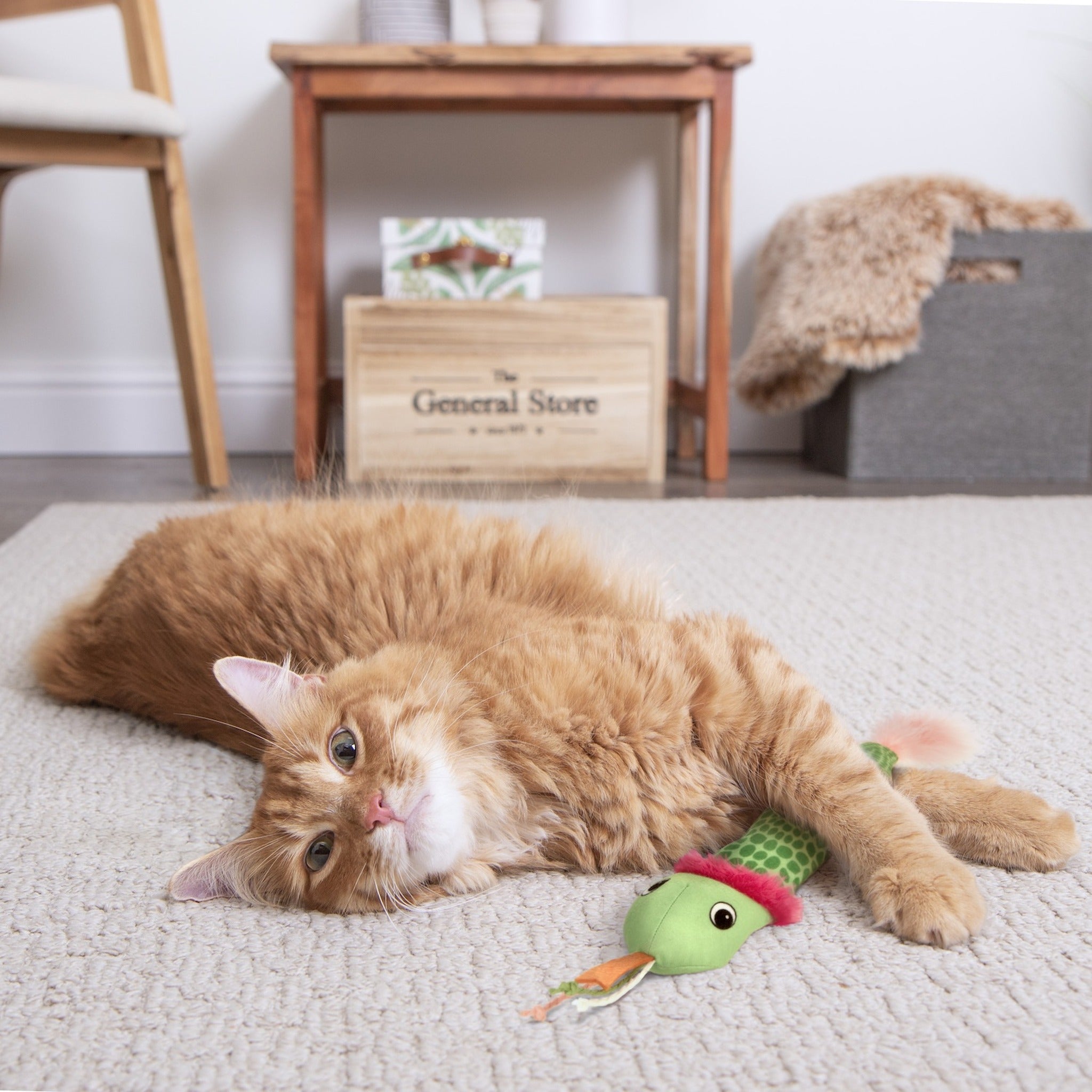 Orange cat wrestling the SmartyKat Crinkle Creeper snake kicker toy on a carpet