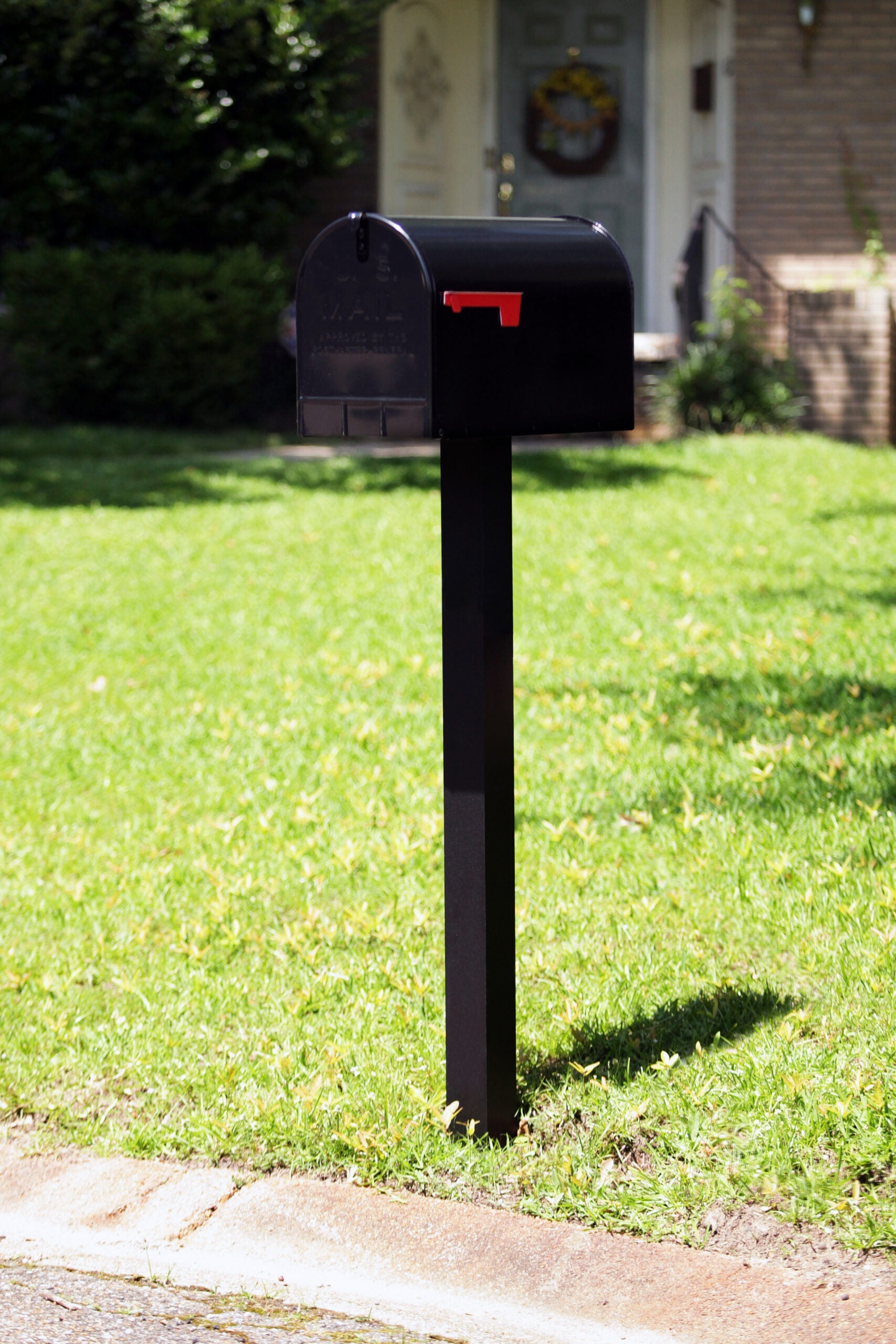 Black Stanley mailbox mounted on a post at a suburban curbside