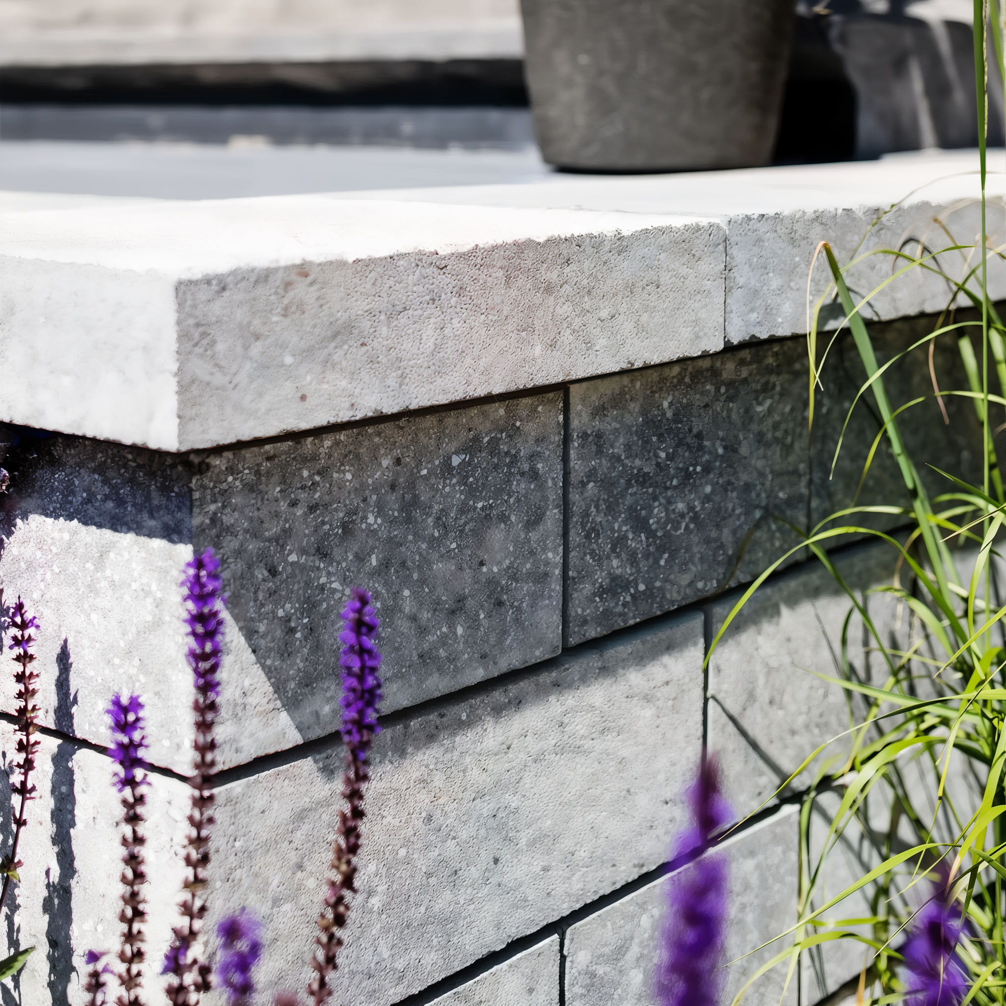 Techo-Bloc Semma Wall Champlain Grey seating wall with garden plantings.