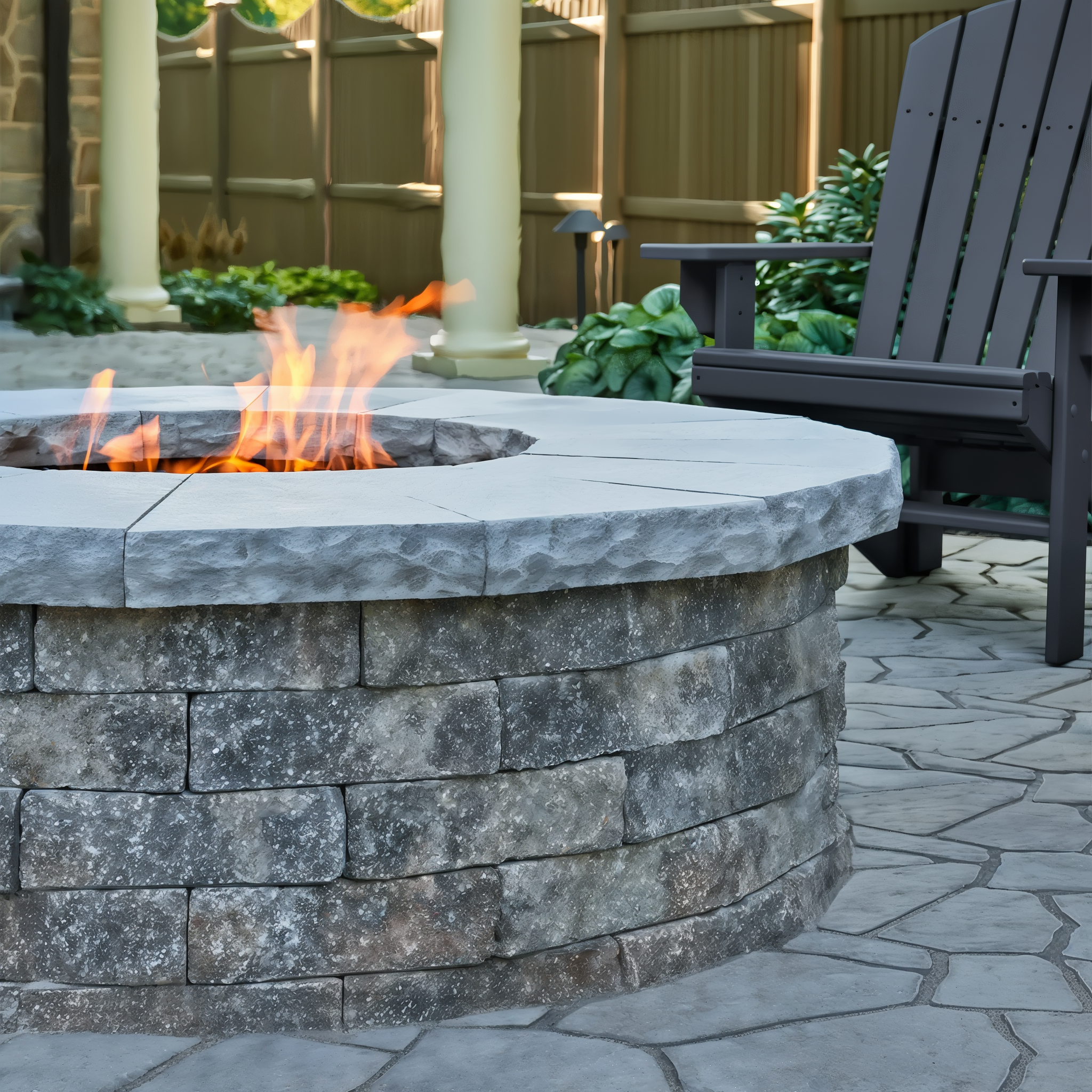 Valencia Fire Pit in Champlain Grey beside a patio seating area.