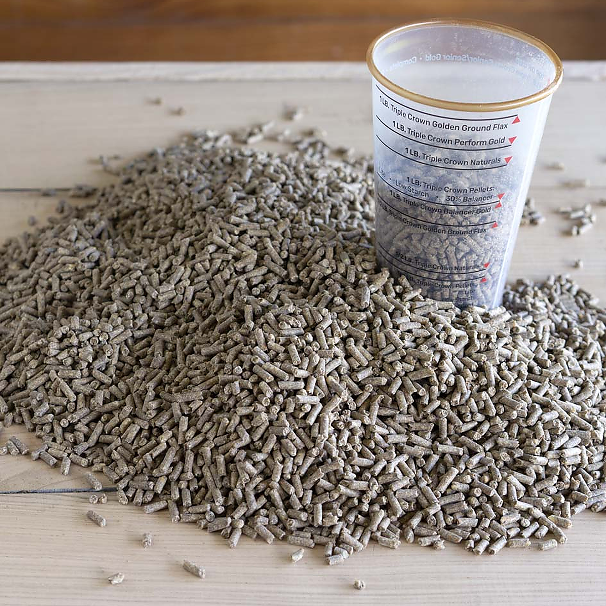 Close-up of Triple Crown Balancer supplement pellets poured beside a feed measuring cup