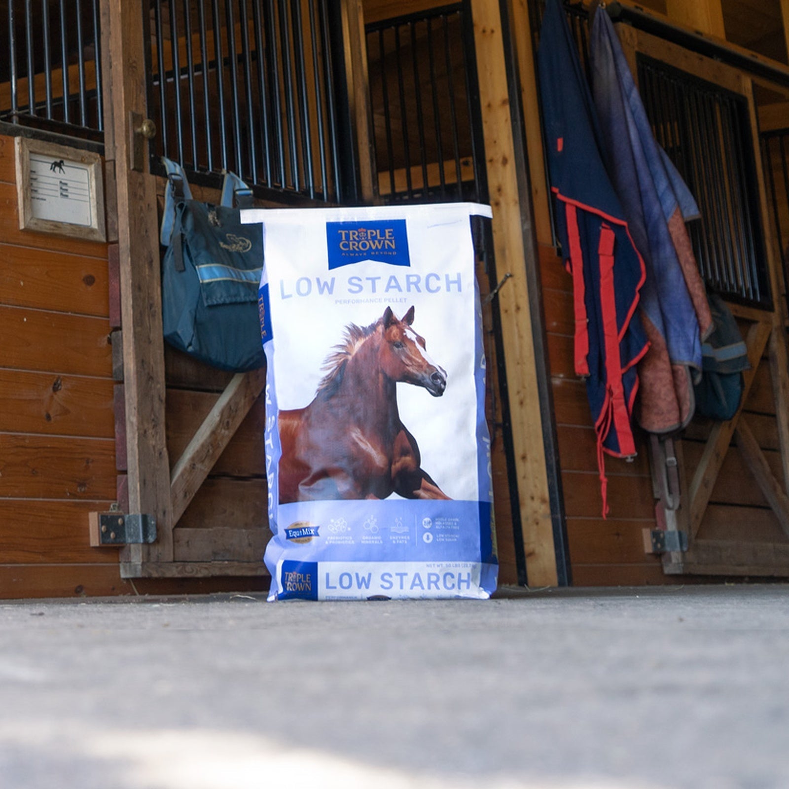 Triple Crown Low Starch 50 lb bag standing in a barn aisle outside the stalls
