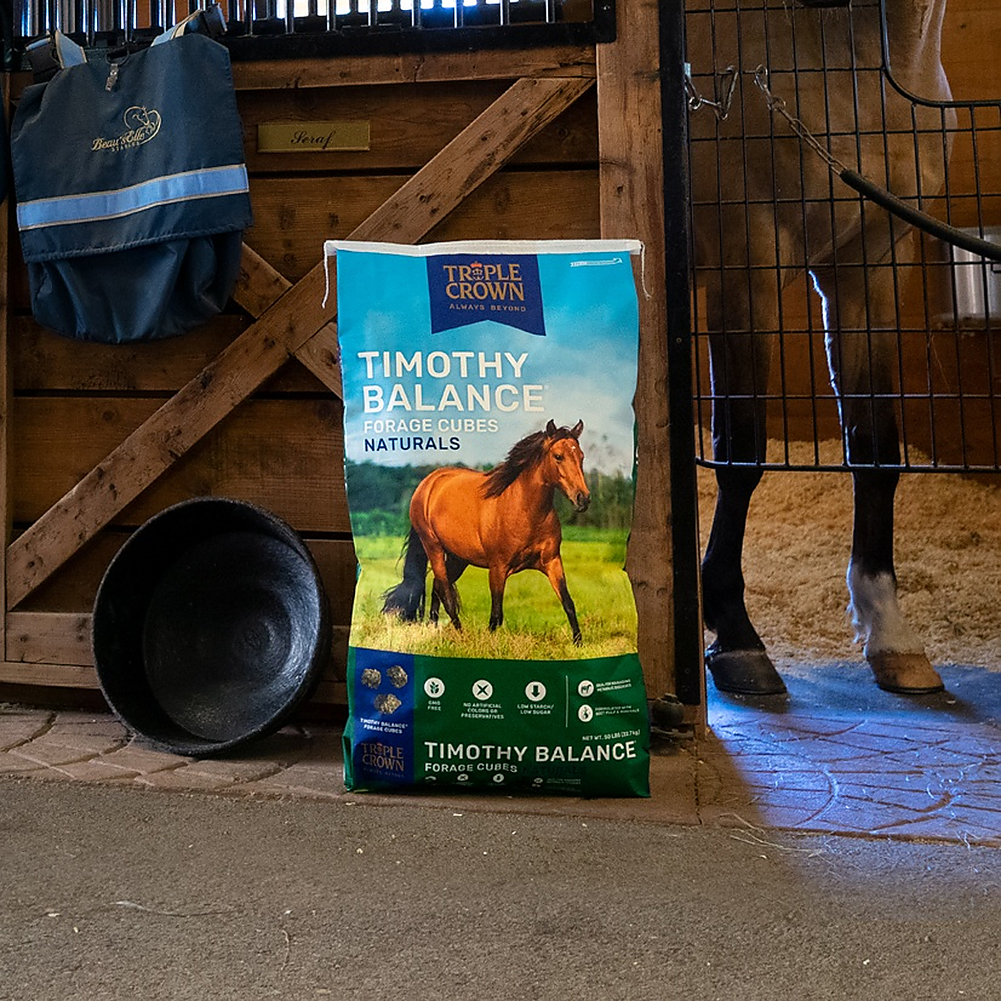 Triple Crown Naturals Timothy Balance Forage Cubes 50 lb bag beside a stall door