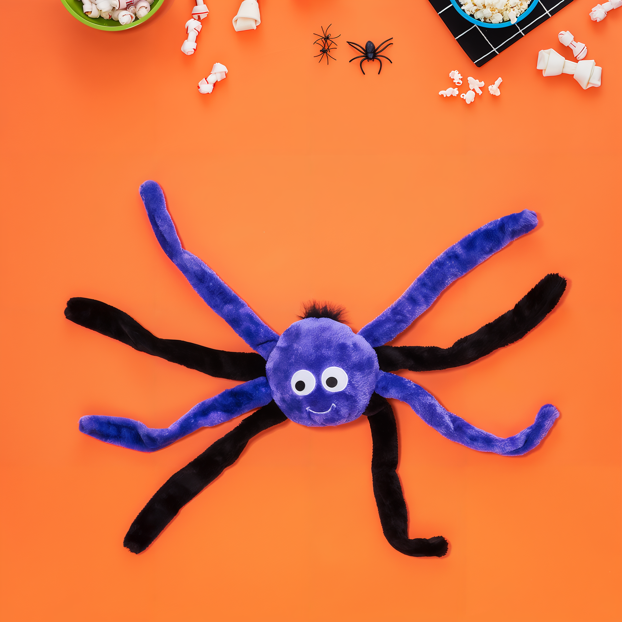 ZippyPaws Halloween Spiderz purple spider dog toy laid out on an orange background with Halloween candy and props